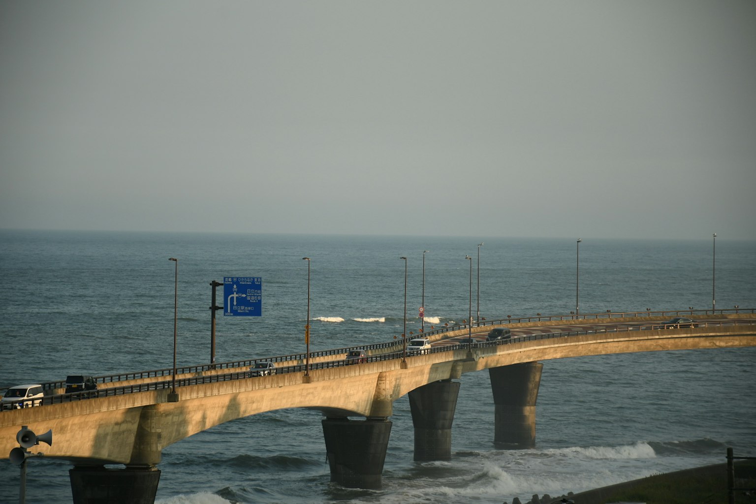 Jembatan di atas laut dengan mobil dan papan biru