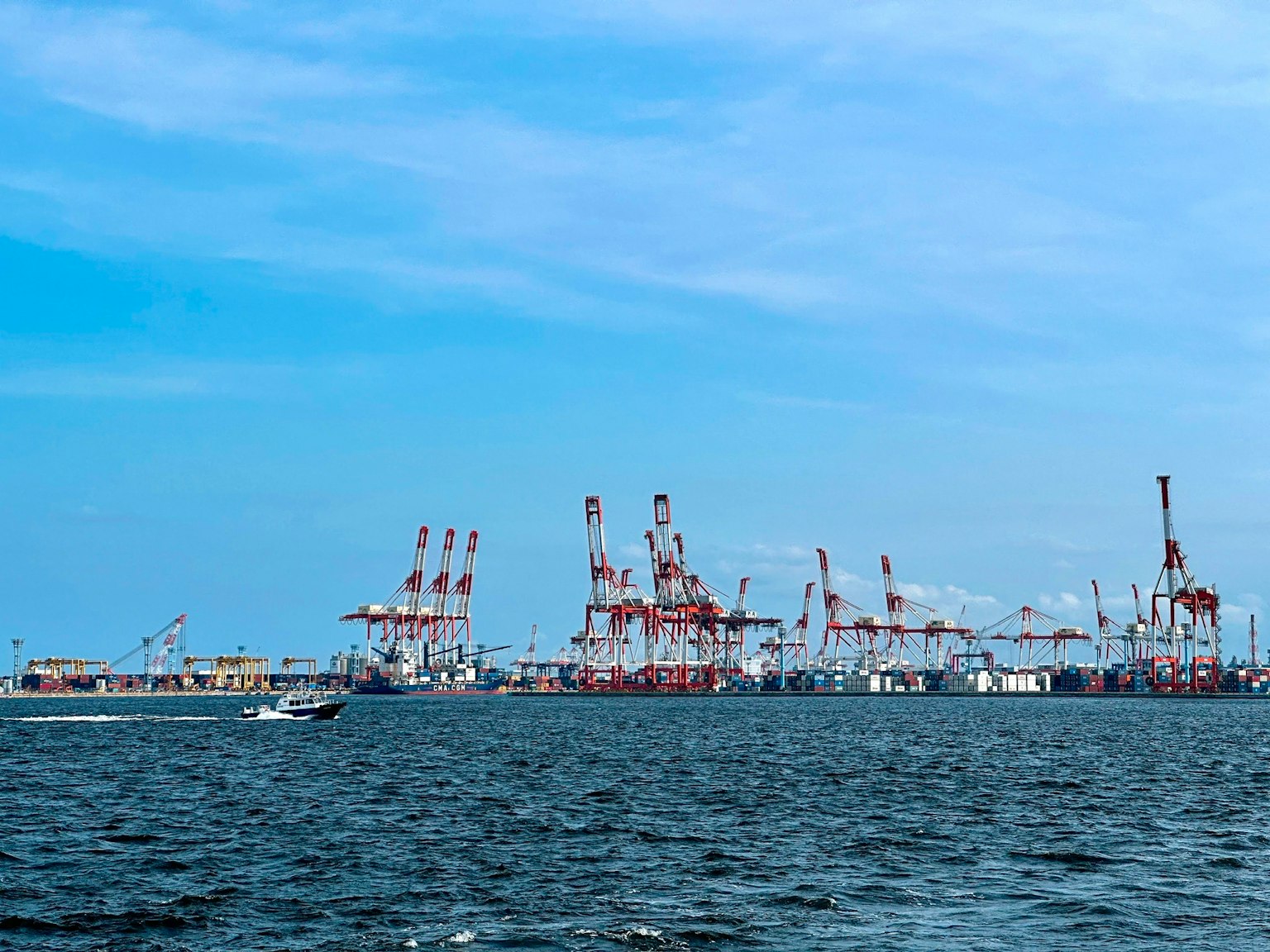 Blick auf einen Hafen mit Kränen und einem Boot auf dem Wasser