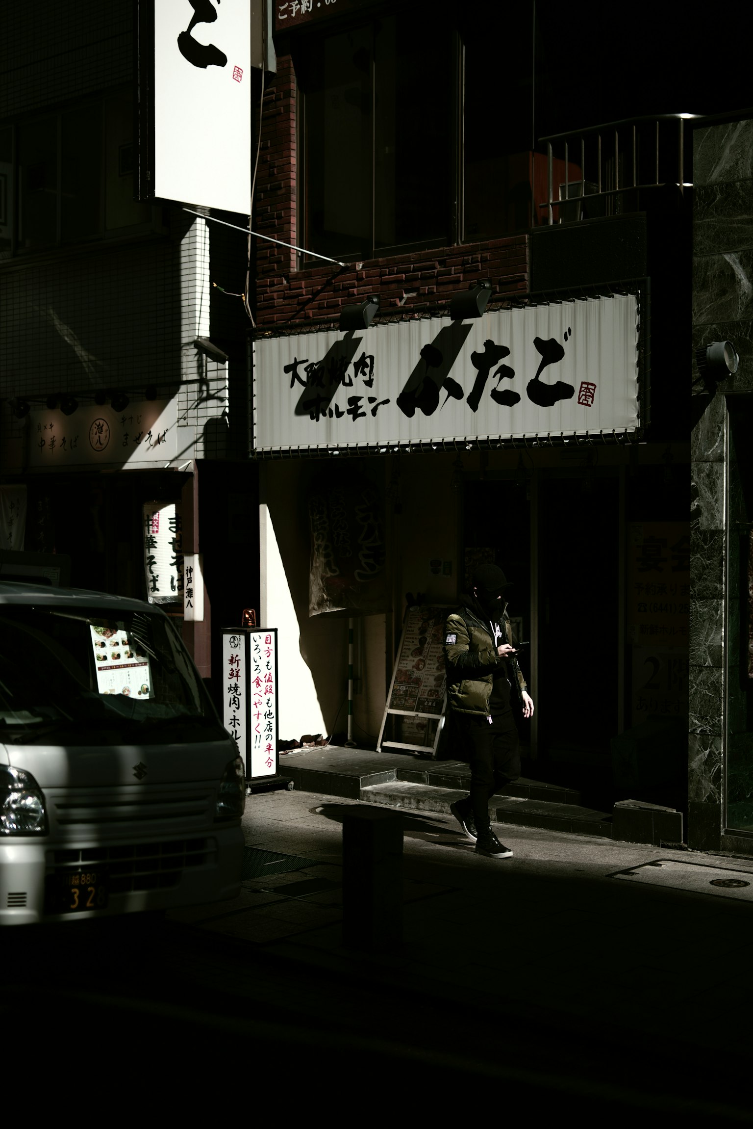 Siluette einer Person vor einem japanischen Restaurant-Schild in einer dunklen Straße