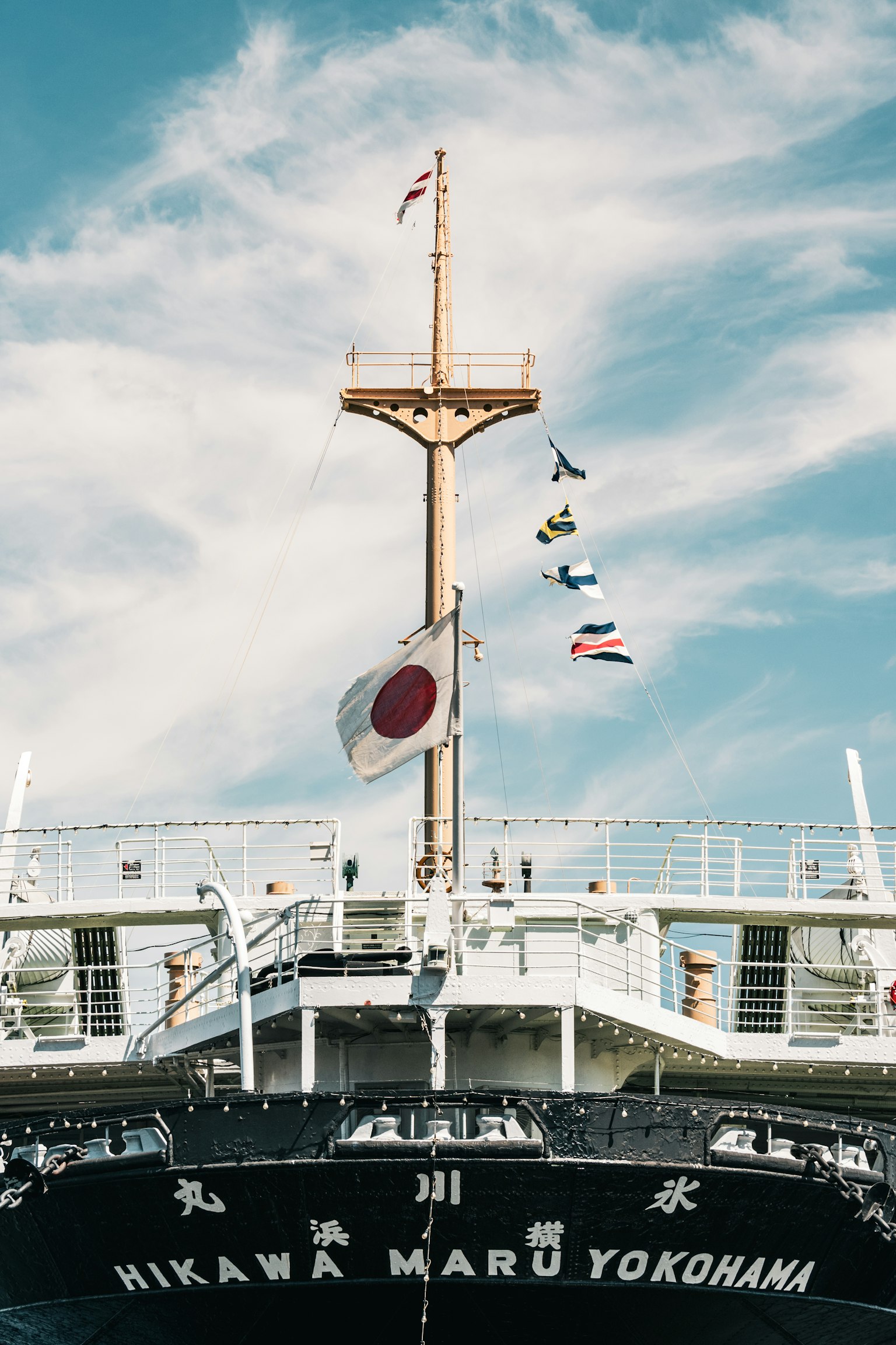 หัวเรือของเรือญี่ปุ่น Hikawa Maru กับธงที่โบกสะบัดใต้ท้องฟ้าสีฟ้า