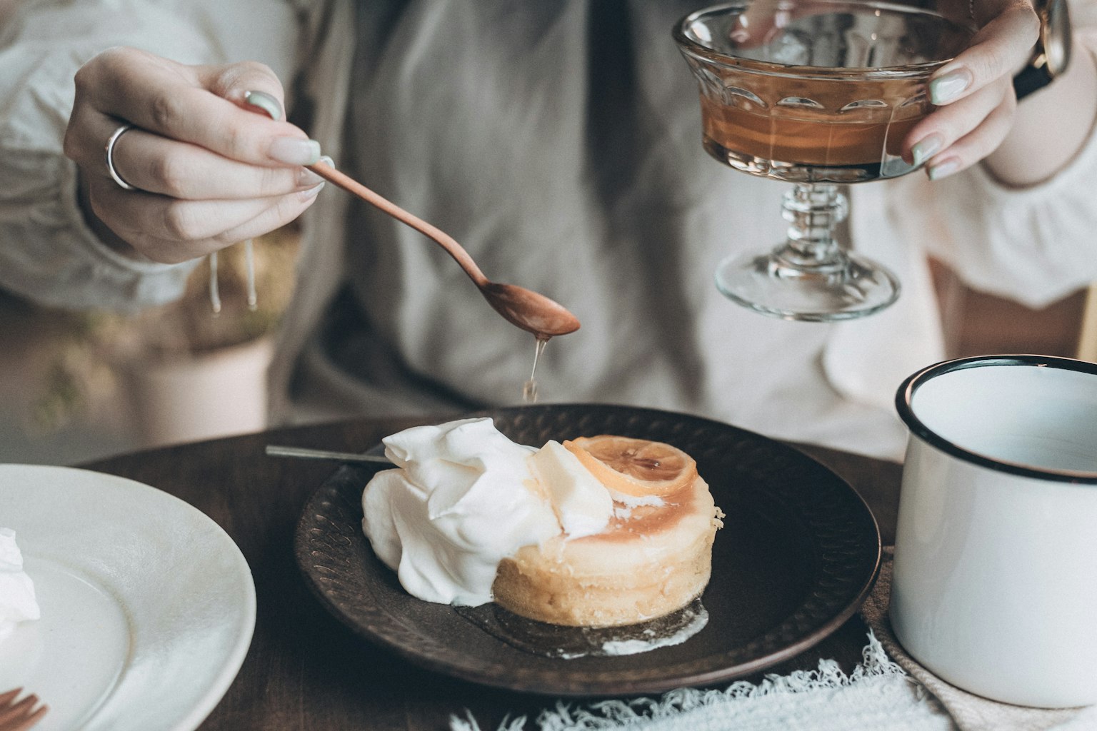 A hand holding a dessert with whipped cream and a drink