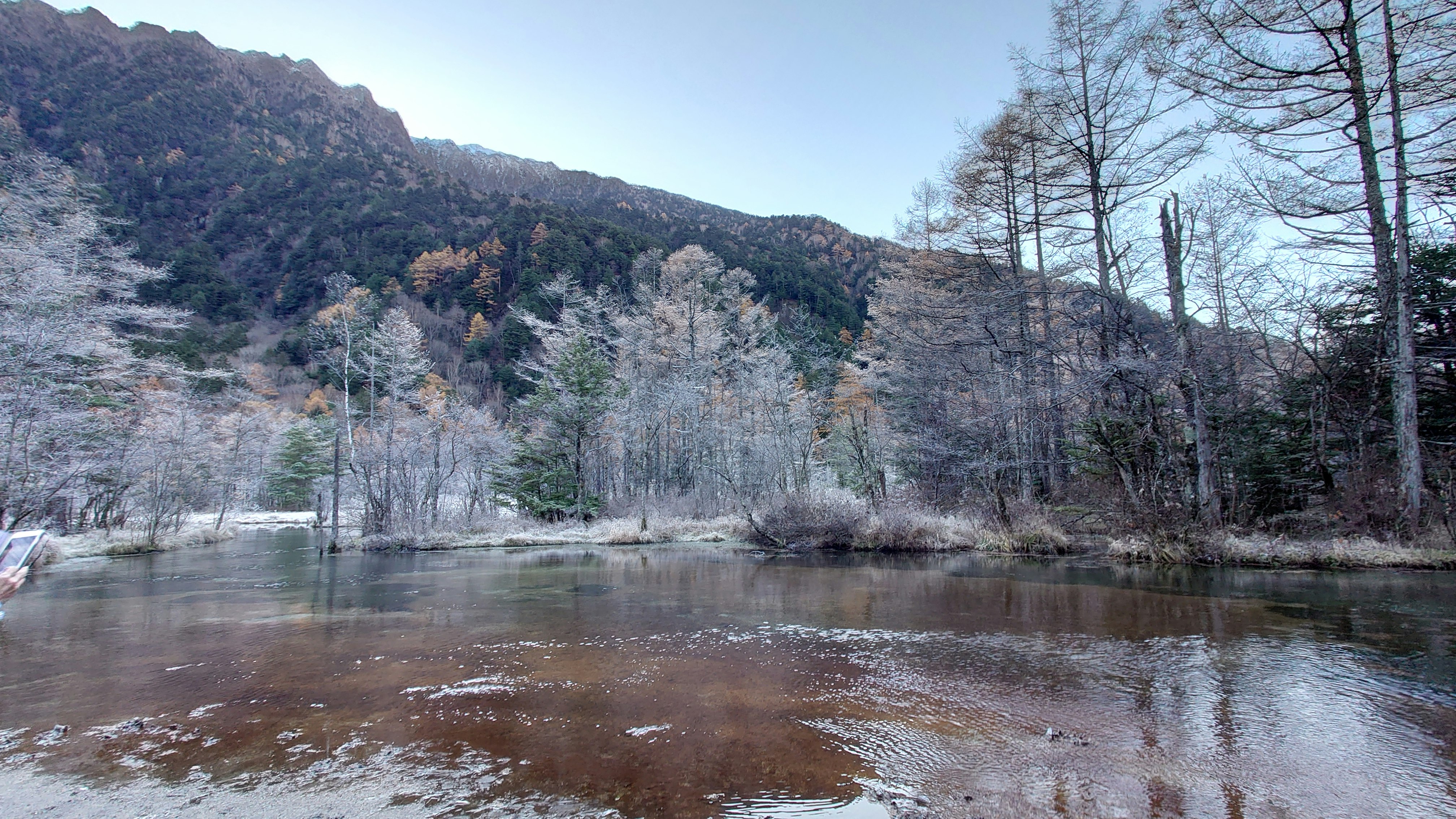 上高地の早朝、雪の残る川沿いの山並みと森