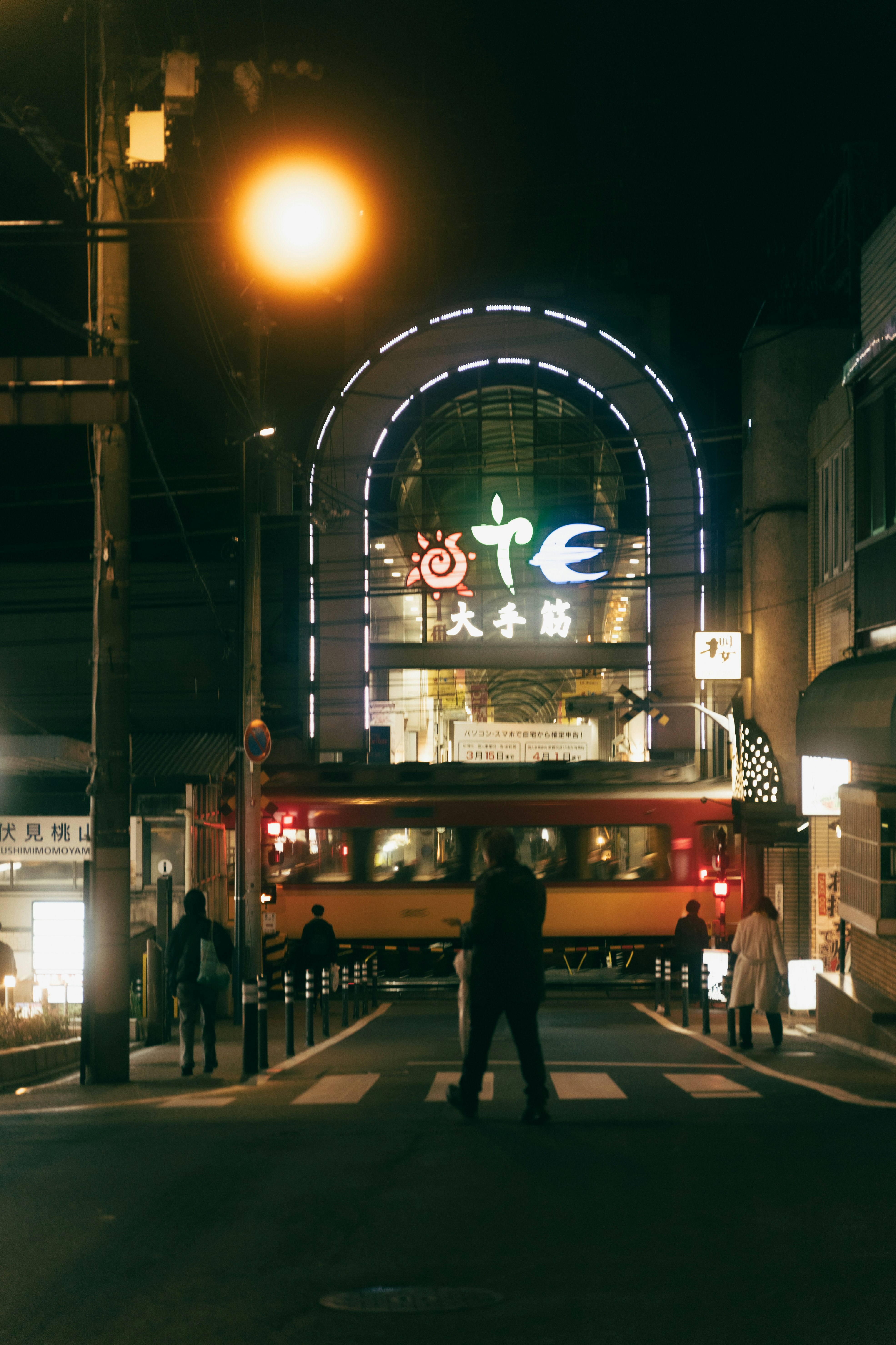 夜のアーチ状の商店街入口とネオン看板のある通り