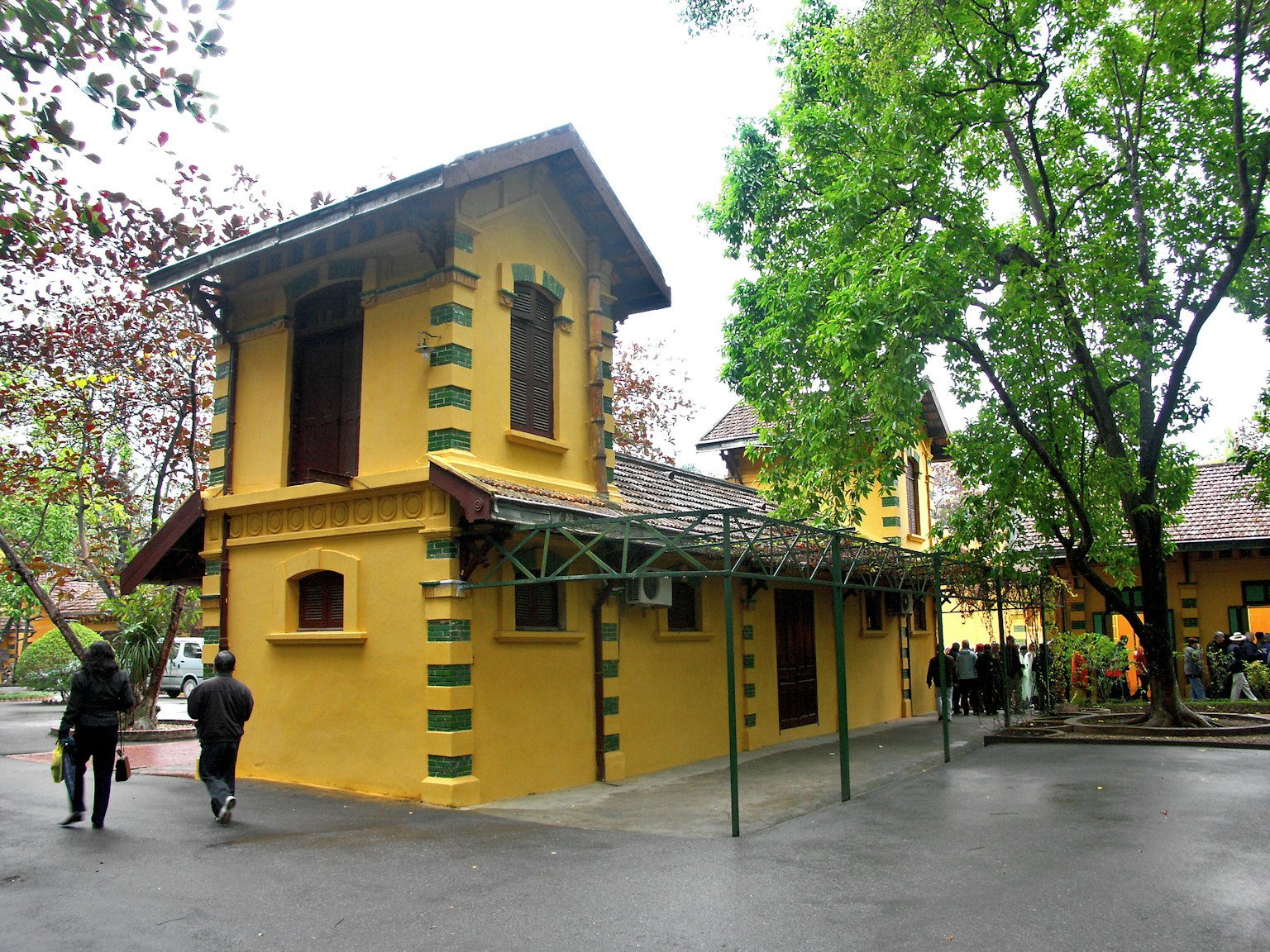 Edificio giallo con decorazioni a strisce verdi circondato da alberi