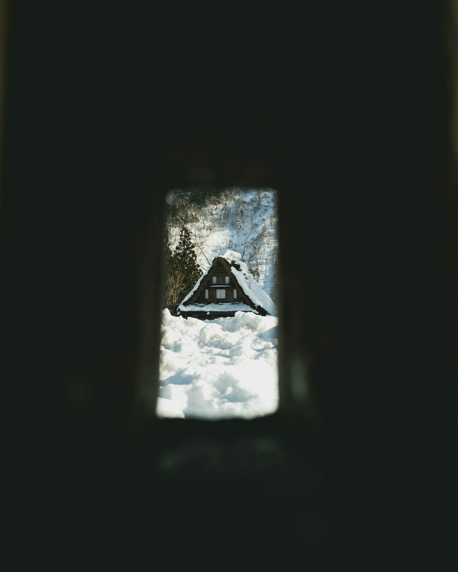 Blick auf ein schneebedecktes Haus durch einen dunklen Tunnel