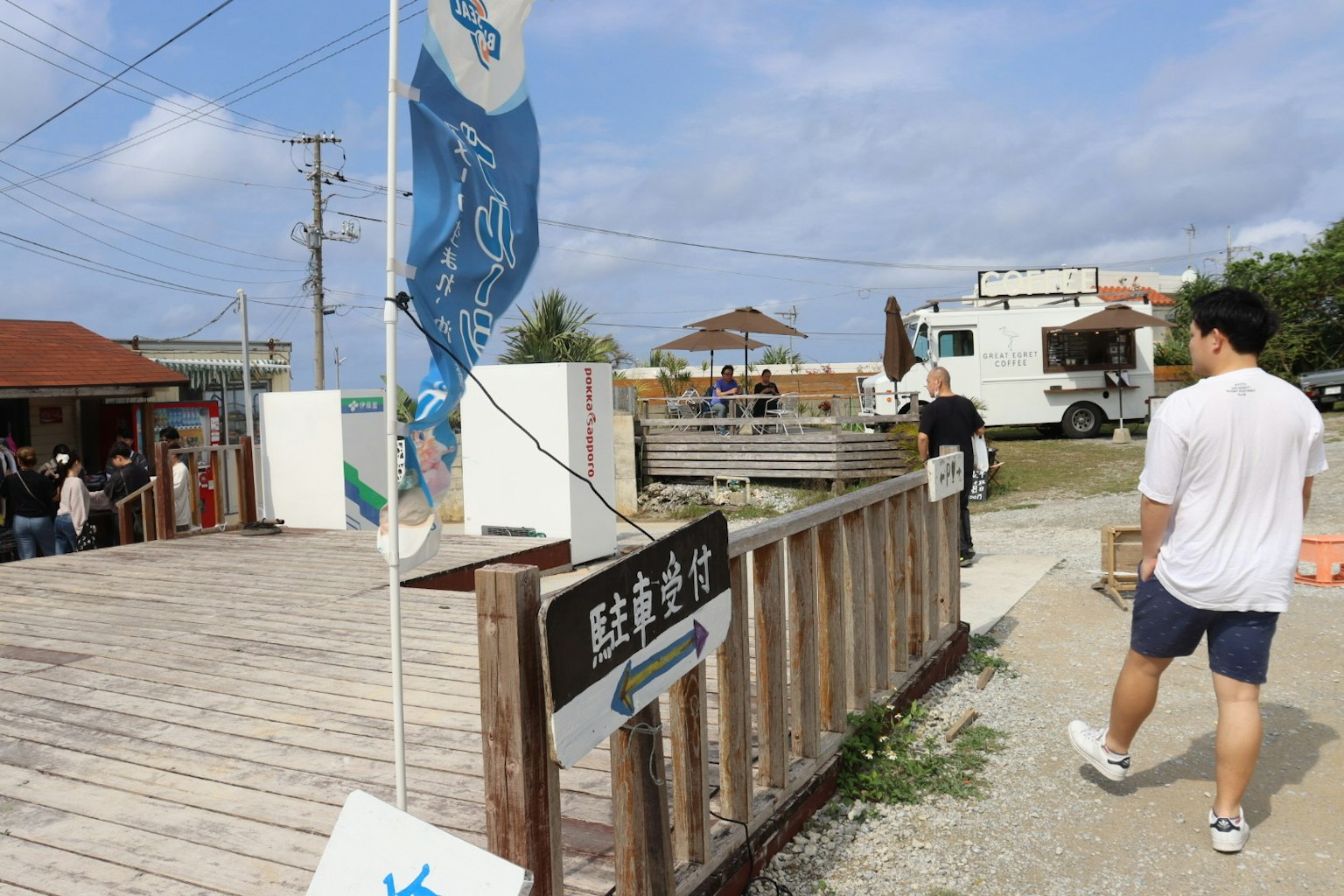 Zone de restauration extérieure avec un drapeau bleu et des gens rassemblés
