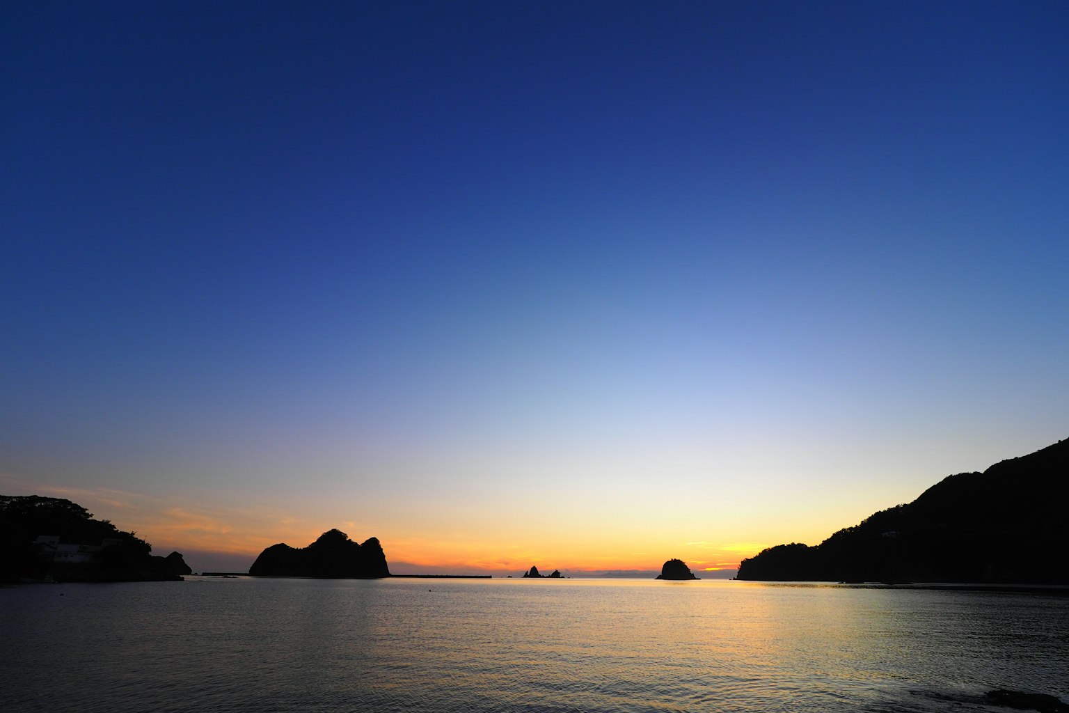 Sonnenuntergang über dem Ozean mit blauem Himmel und orangefarbenen Reflexionen auf dem Wasser