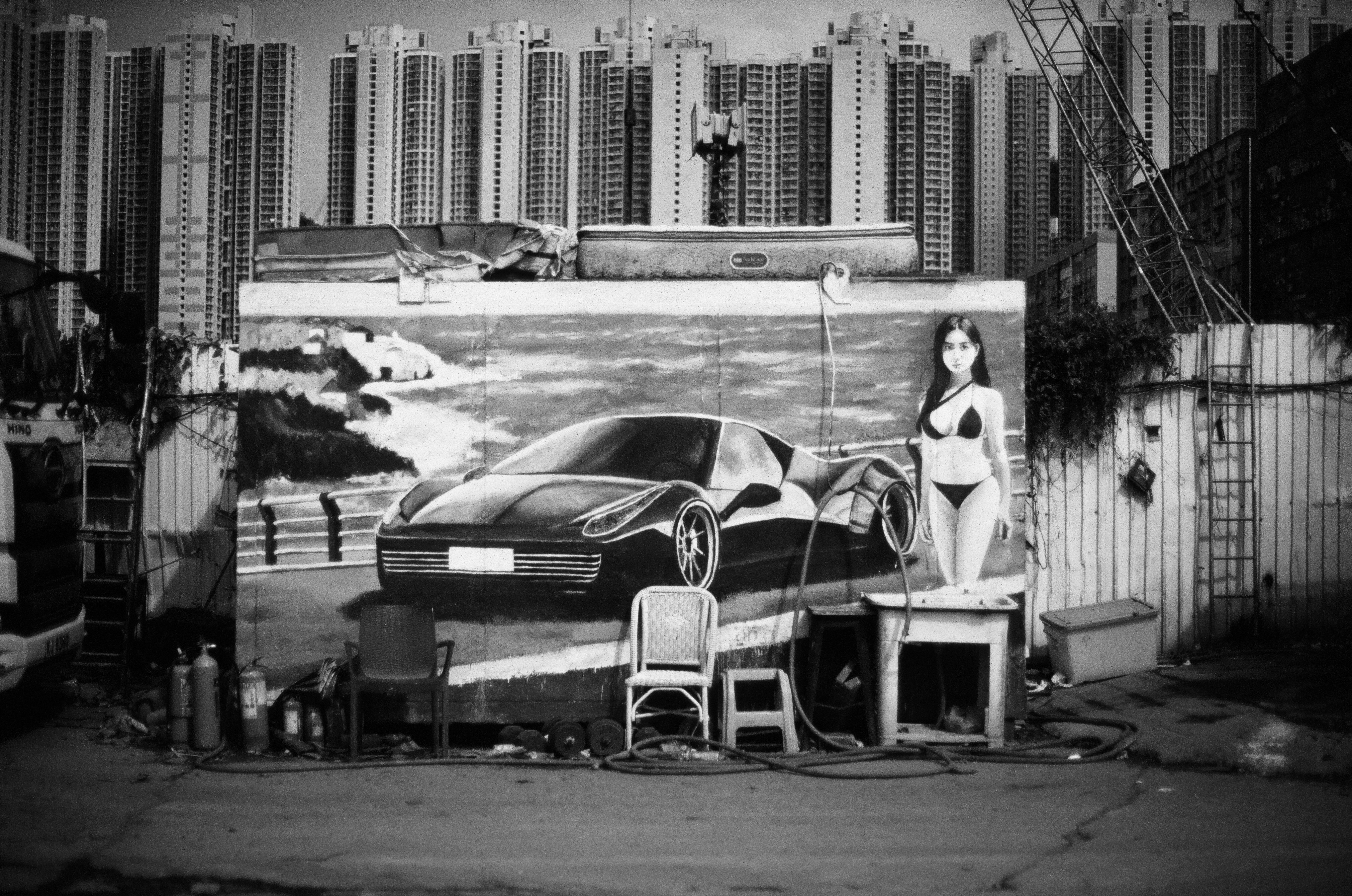 高層ビルを背景にした車の壁画とモデルのポーズのある路地
