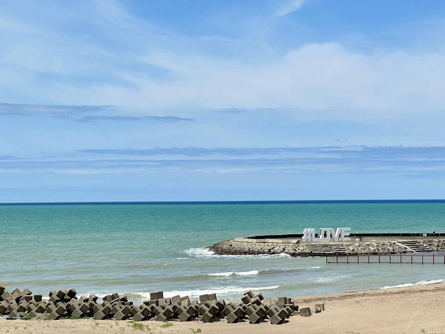 Vista escénica del mar azul y el cielo tranquilo con escultura de texto blanco