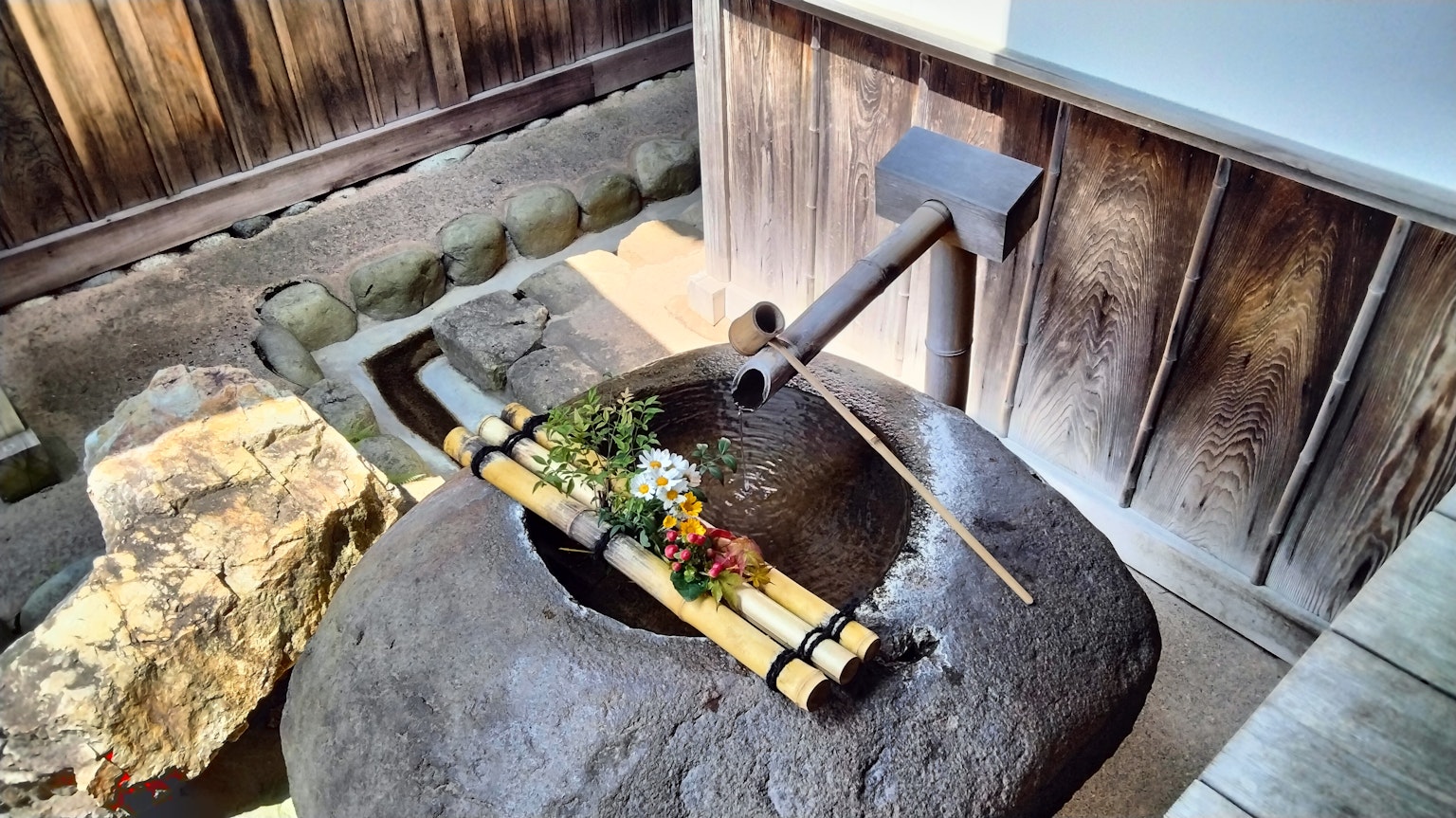 Élément de jardin japonais avec un bassin en pierre décoré de bambou et de fleurs