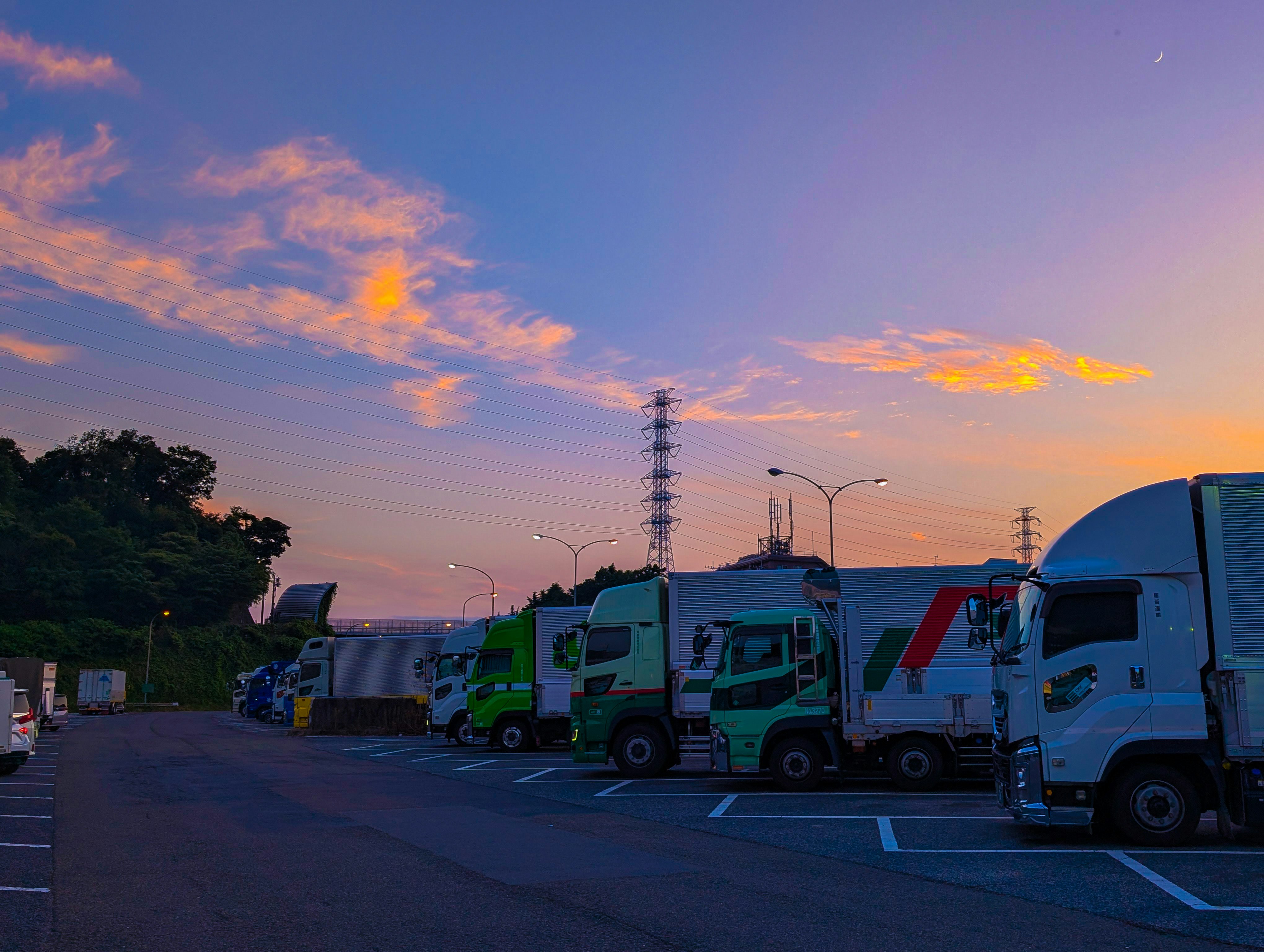 夕方の高速道路PAで並ぶトラックと空の夕焼け