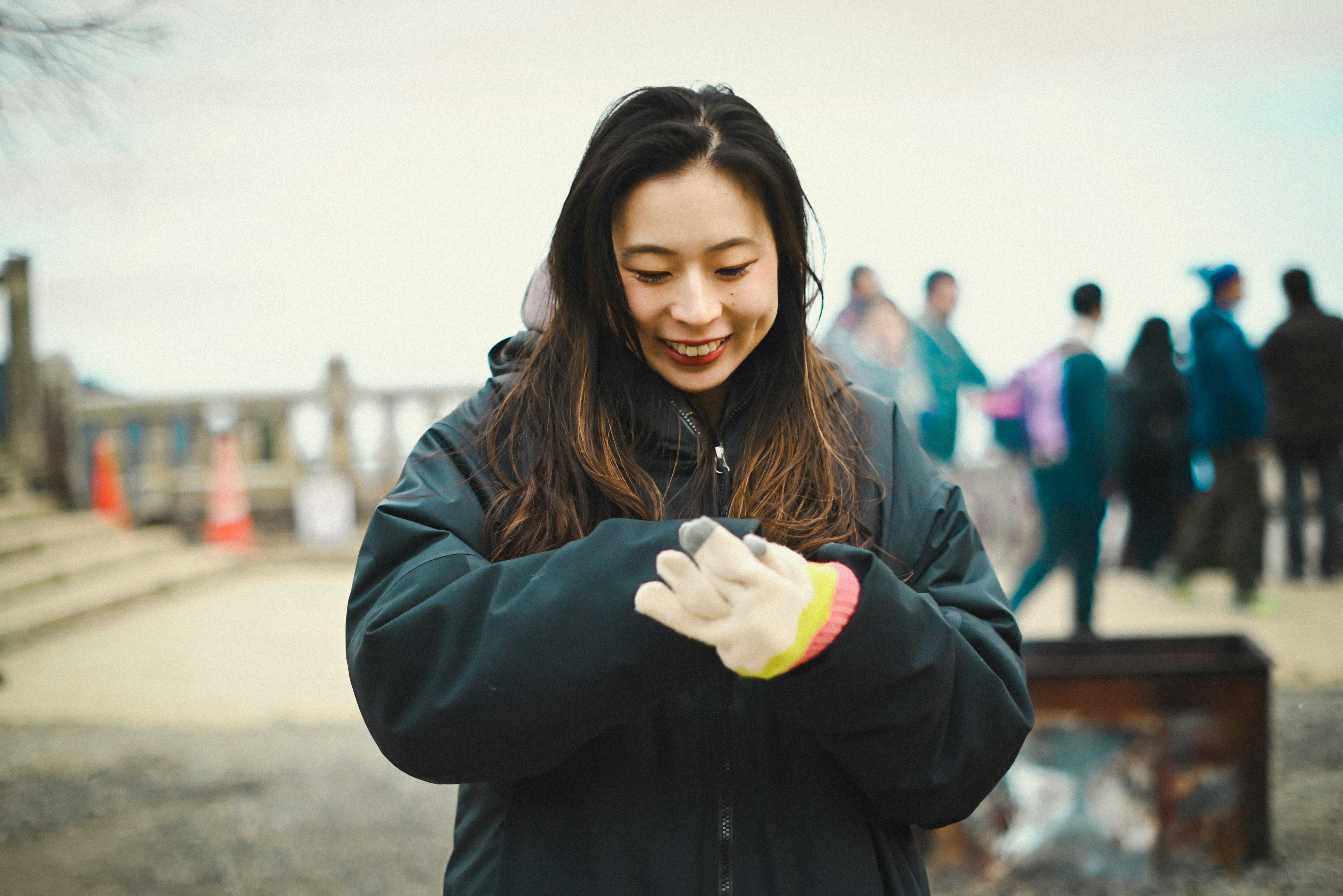 Mujer sonriente poniéndose guantes al aire libre, cuidándolos