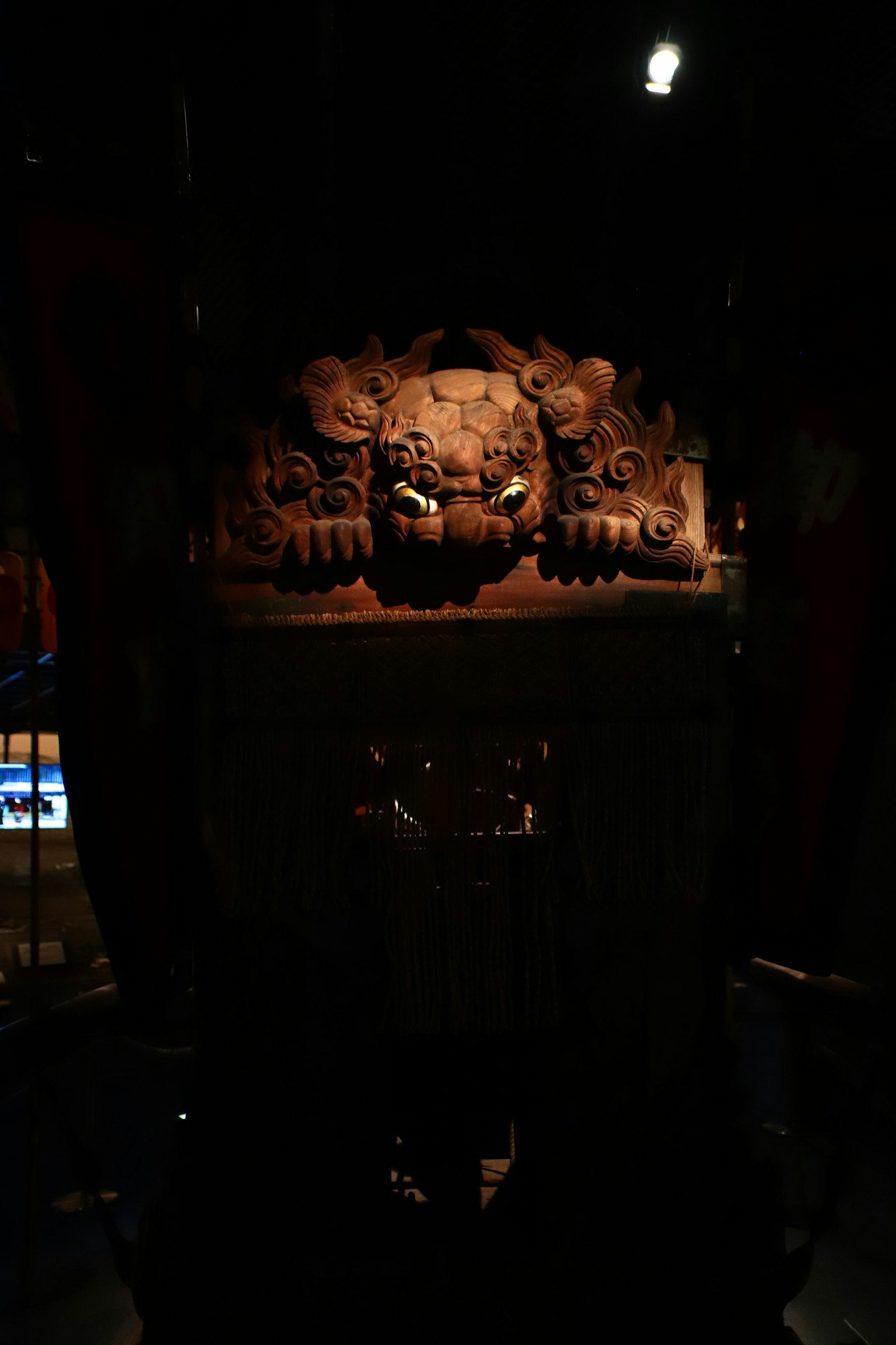 Scultura di testa di leone intagliata con un piedistallo ornato in un ambiente scuro