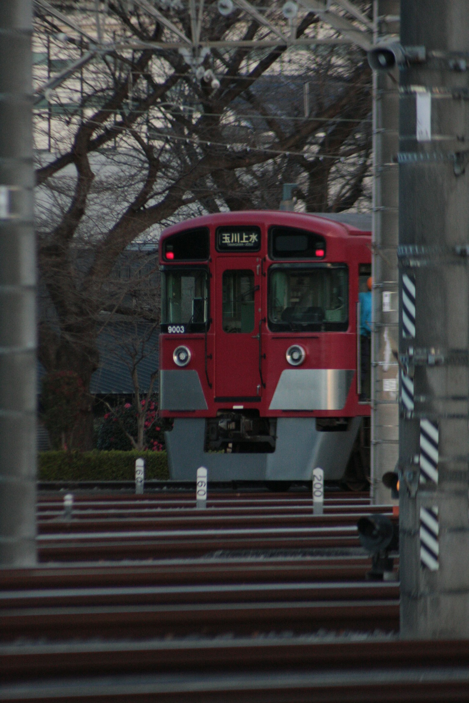 Red train approaching on tracks with trees in background