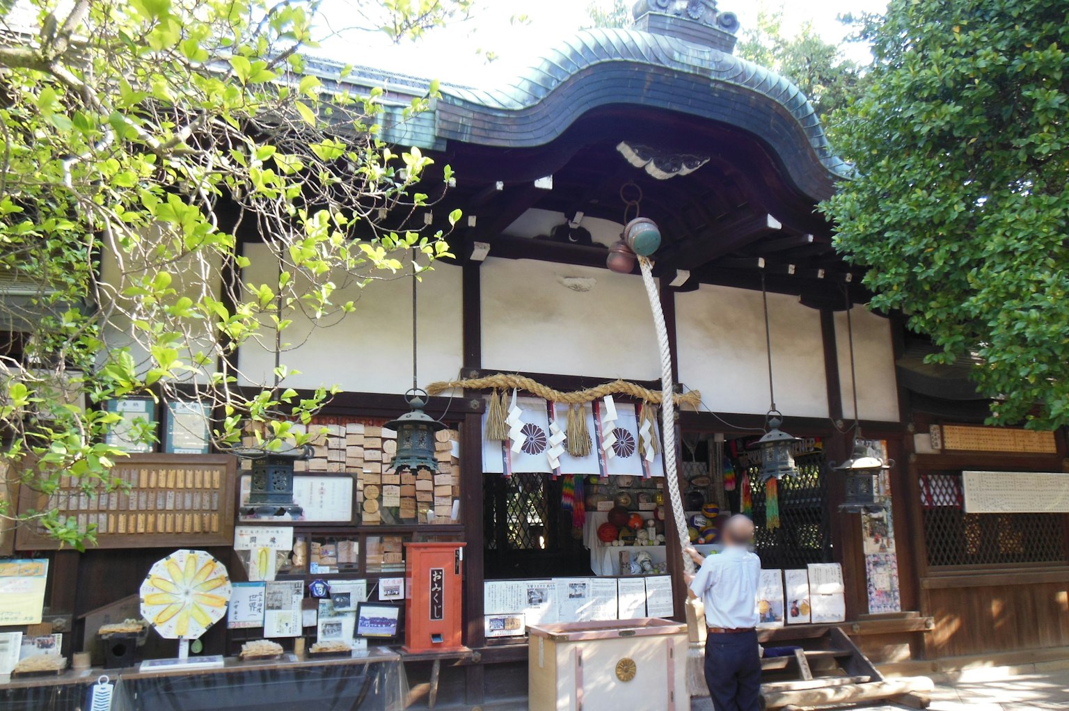 Traditional Japanese shrine exterior with wooden walls and roof surrounded by greenery