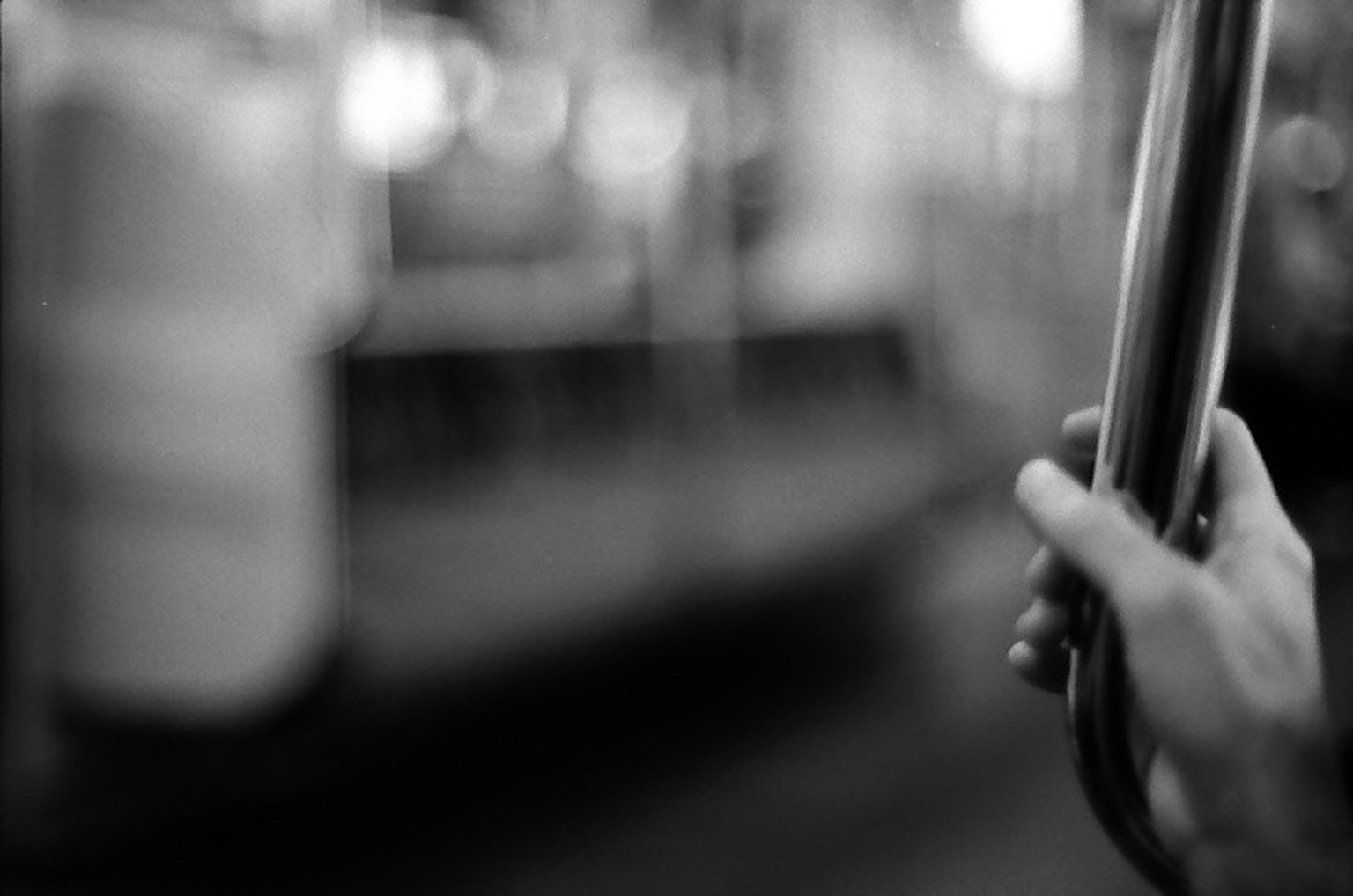 A hand holding a pole in a black and white train interior