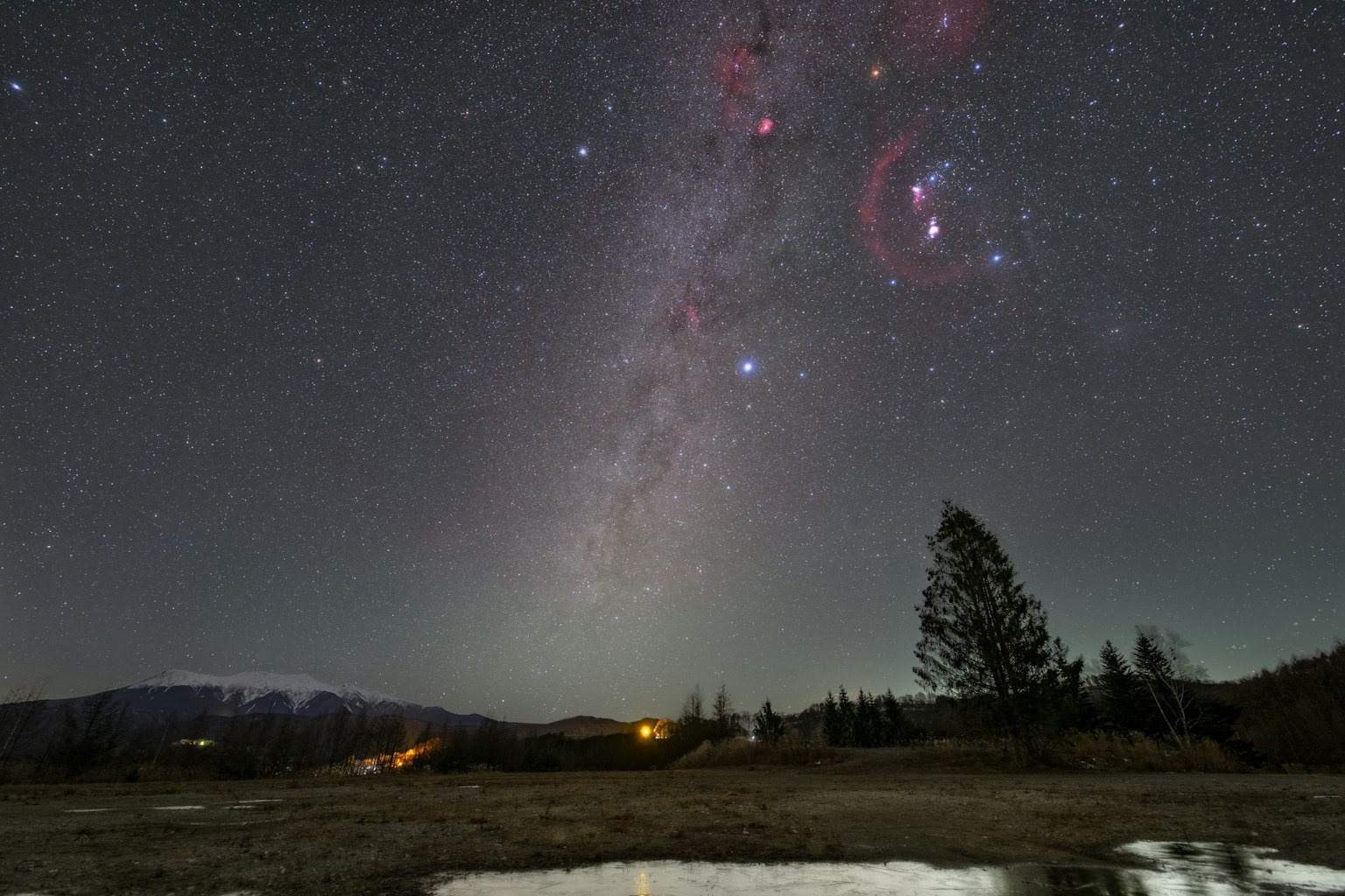 Vista della Via Lattea sotto un cielo stellato con riflessi in una pozzanghera