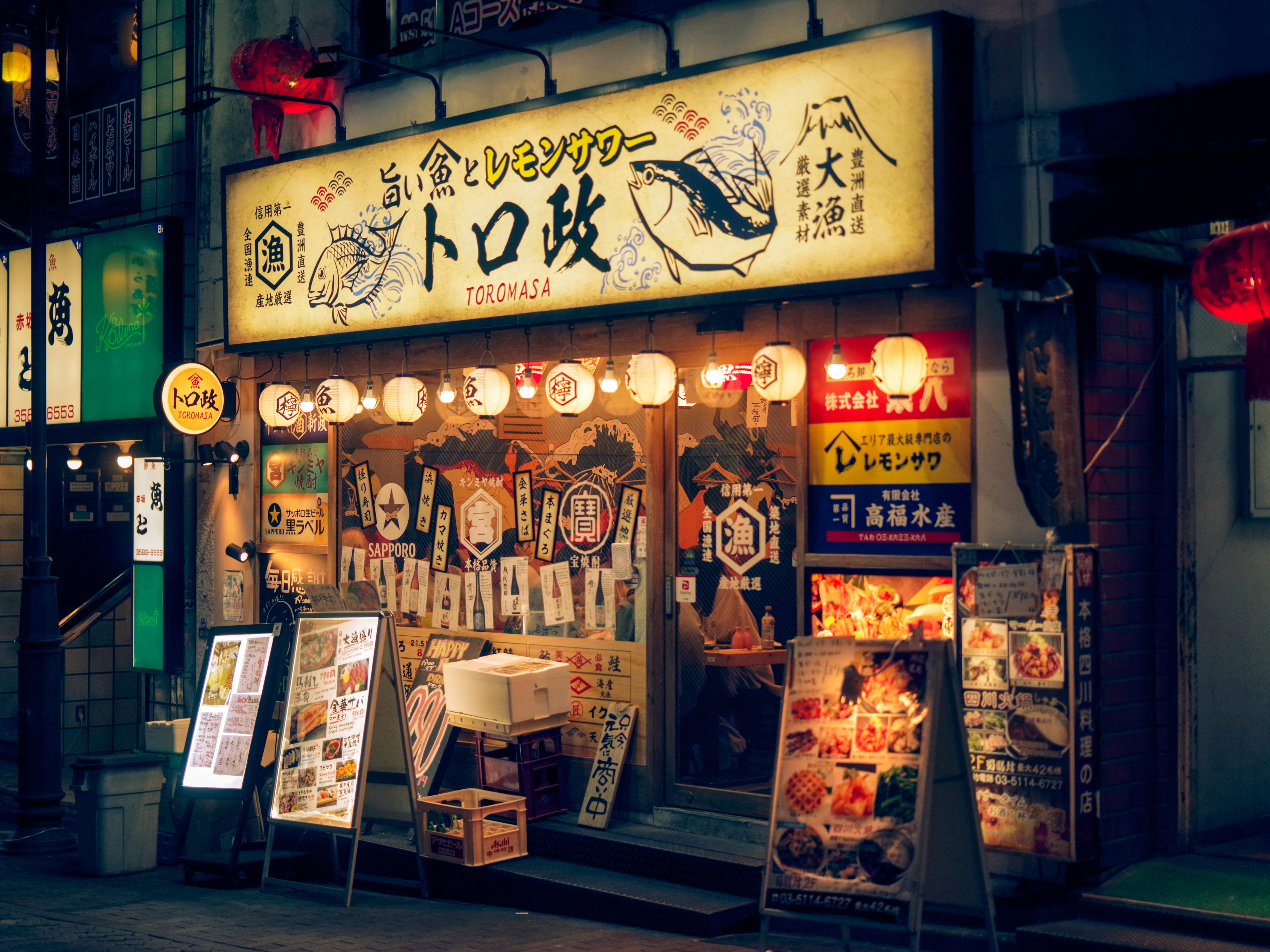夜の路地に並ぶ居酒屋の看板と提灯