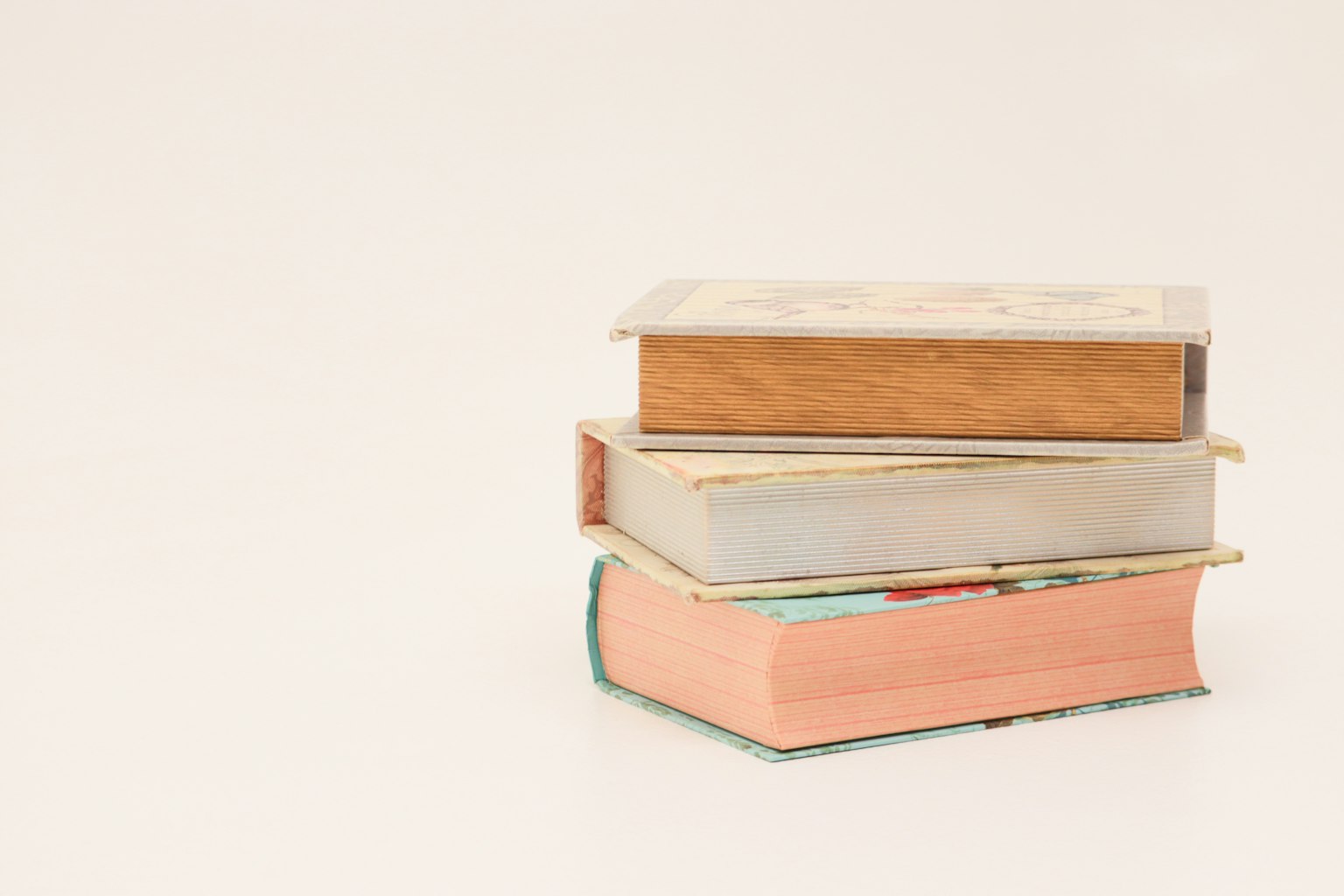 Pile de trois livres avec des couleurs variées et une couverture en bois