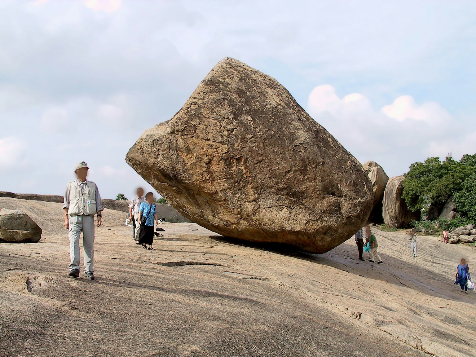 People standing near a large boulder on rocky terrain