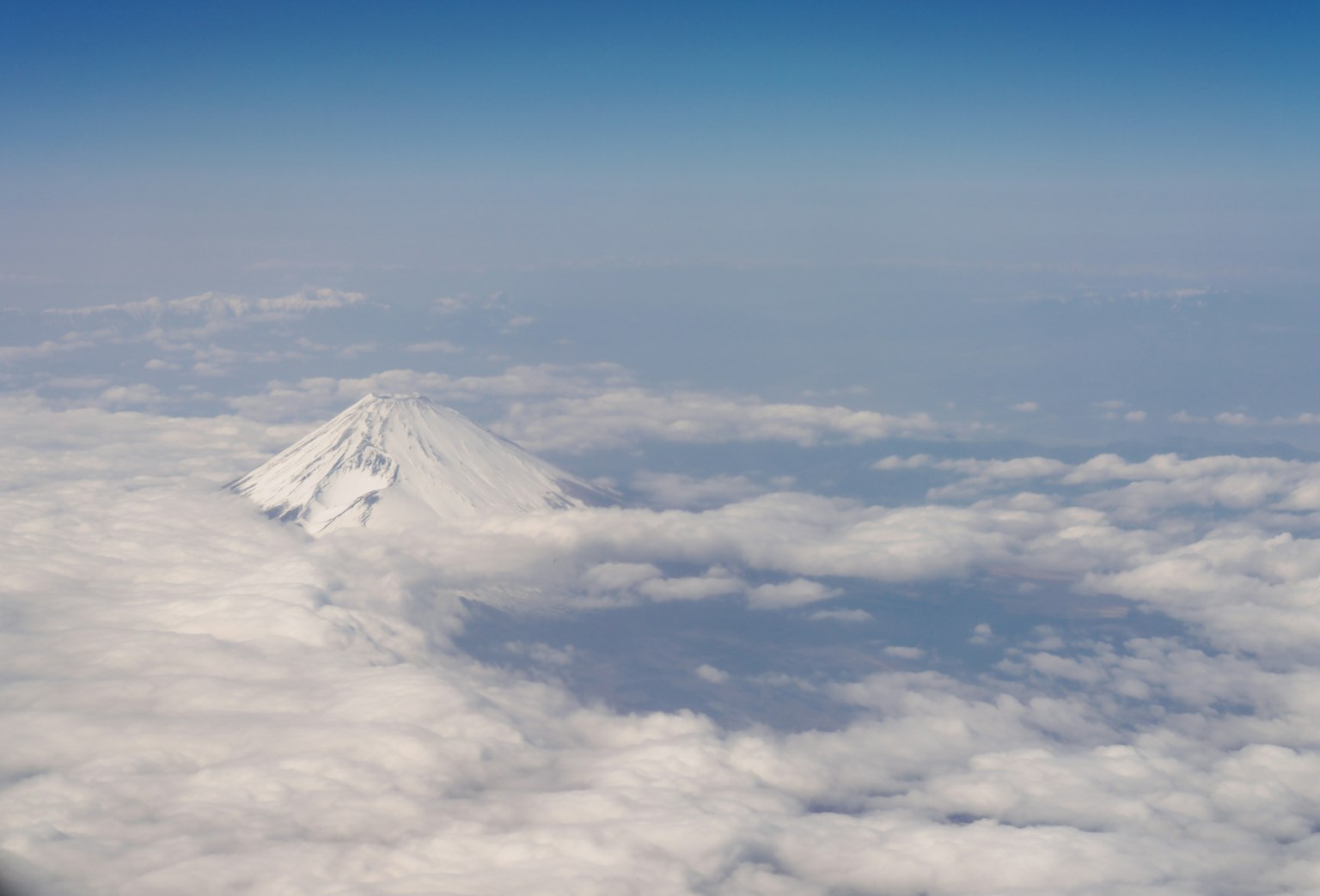 雪山在晴朗藍天中高聳於雲層之上