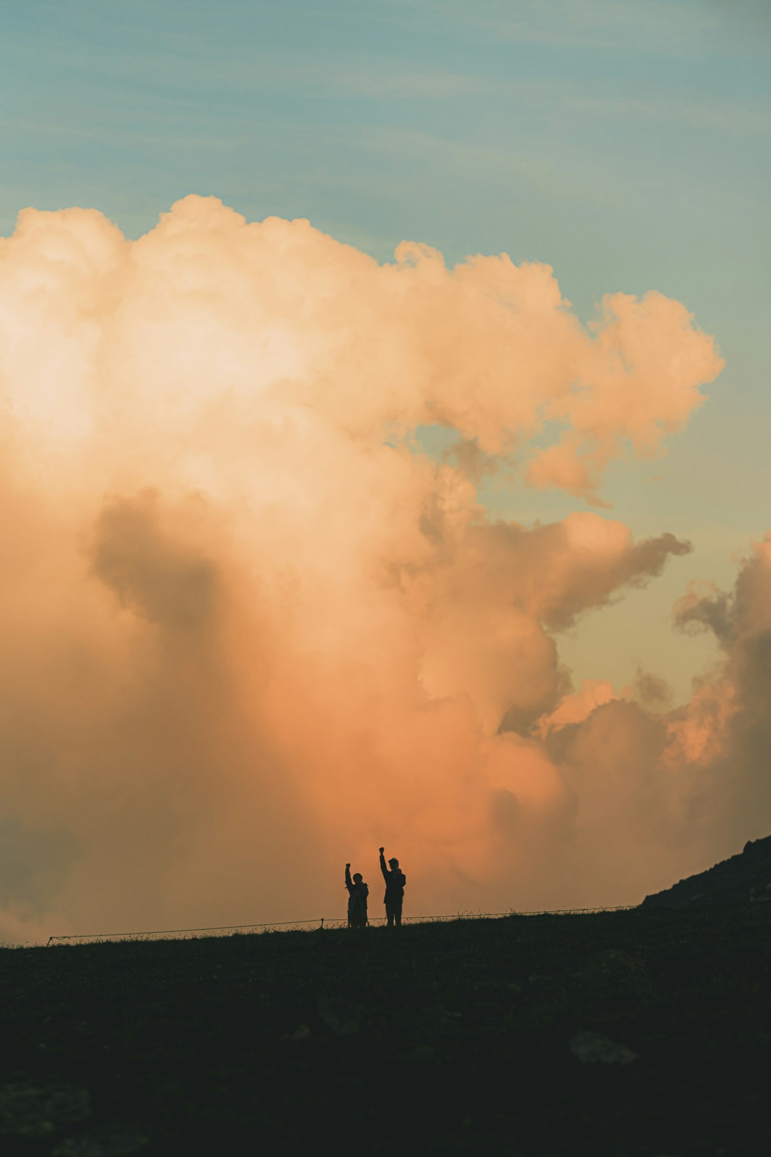Silhouette of two people against a sunset sky