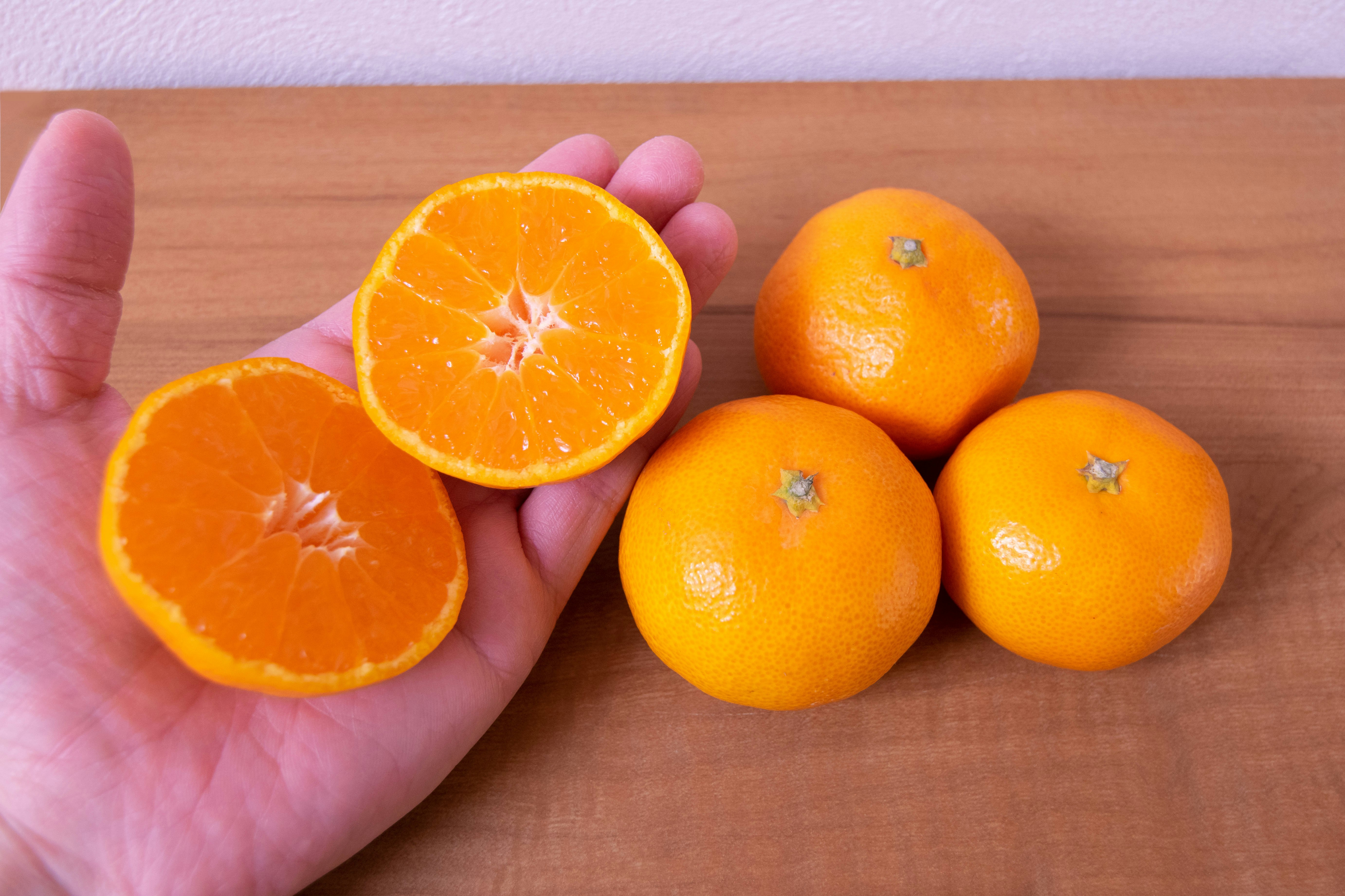 Hand hält Orangen mit sichtbaren Querschnitten