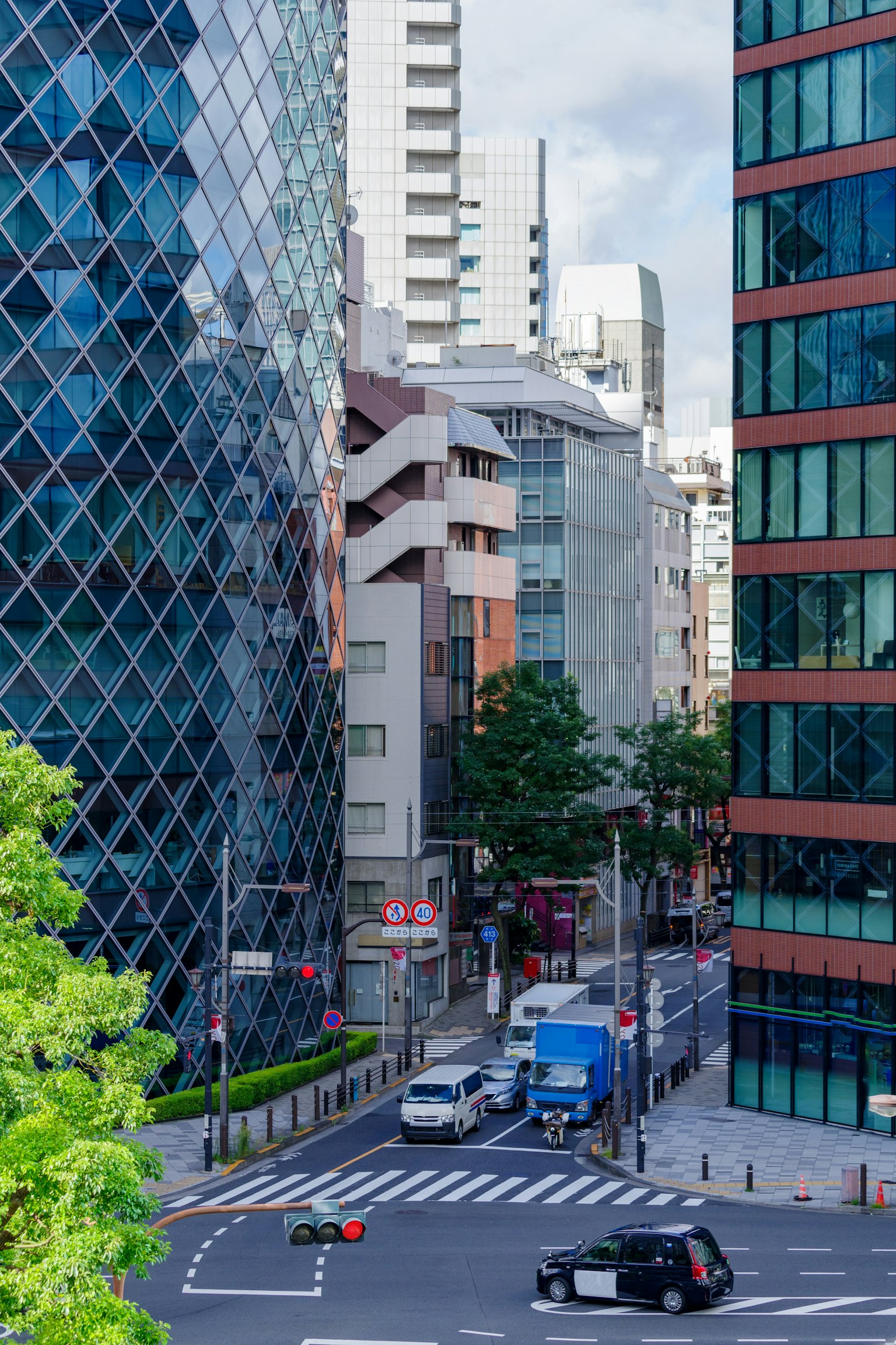 Pemandangan kota Tokyo dengan gedung modern dan persimpangan sibuk dikelilingi pepohonan