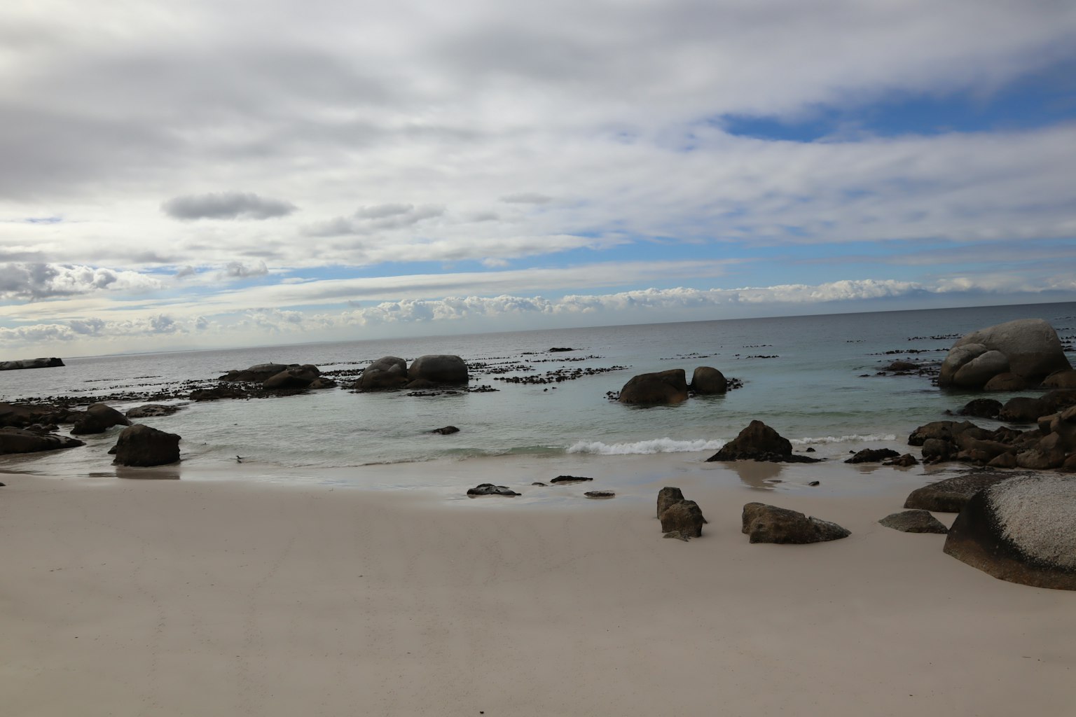 Pemandangan pantai tenang dengan laut tenang dan batu-batu