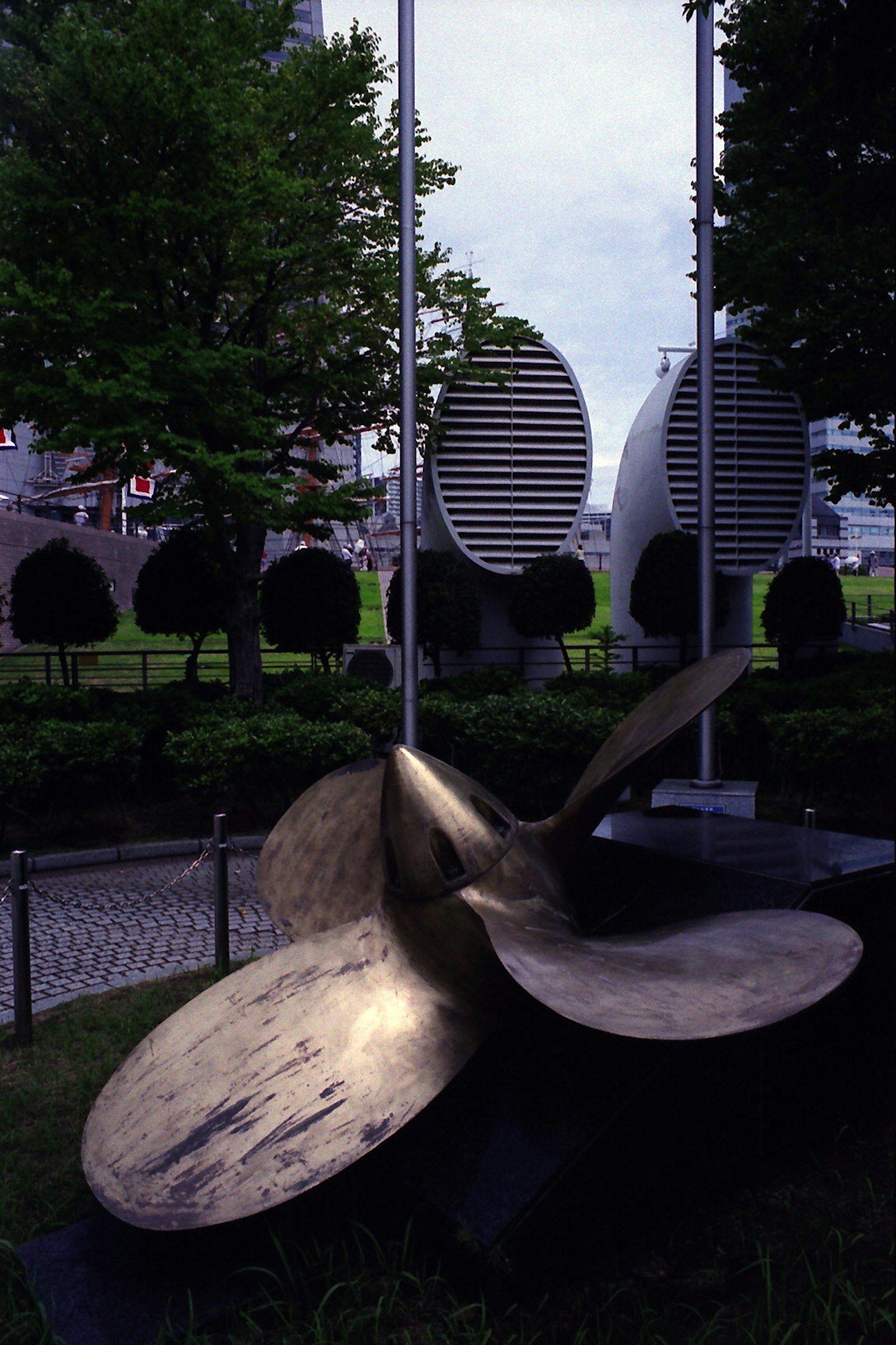 Scultura in metallo in un parco con strutture circolari sullo sfondo