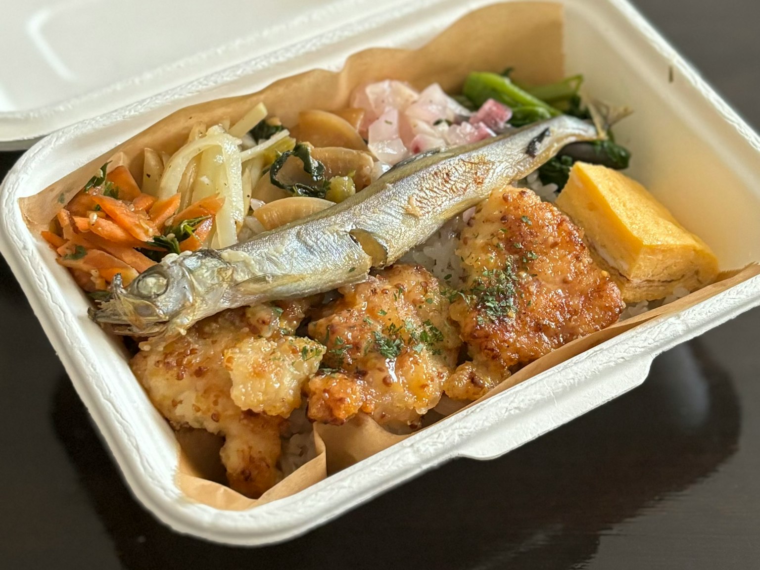 便當盒內有烤魚、炸物、蛋卷和蔬菜配菜