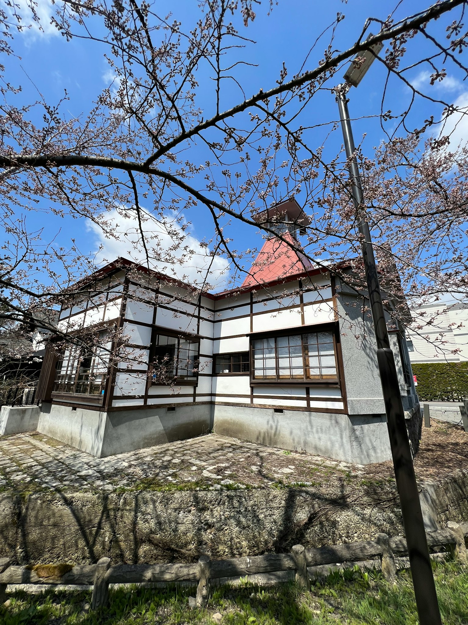Rumah tradisional Jepang di depan pohon sakura langit biru dan awan putih