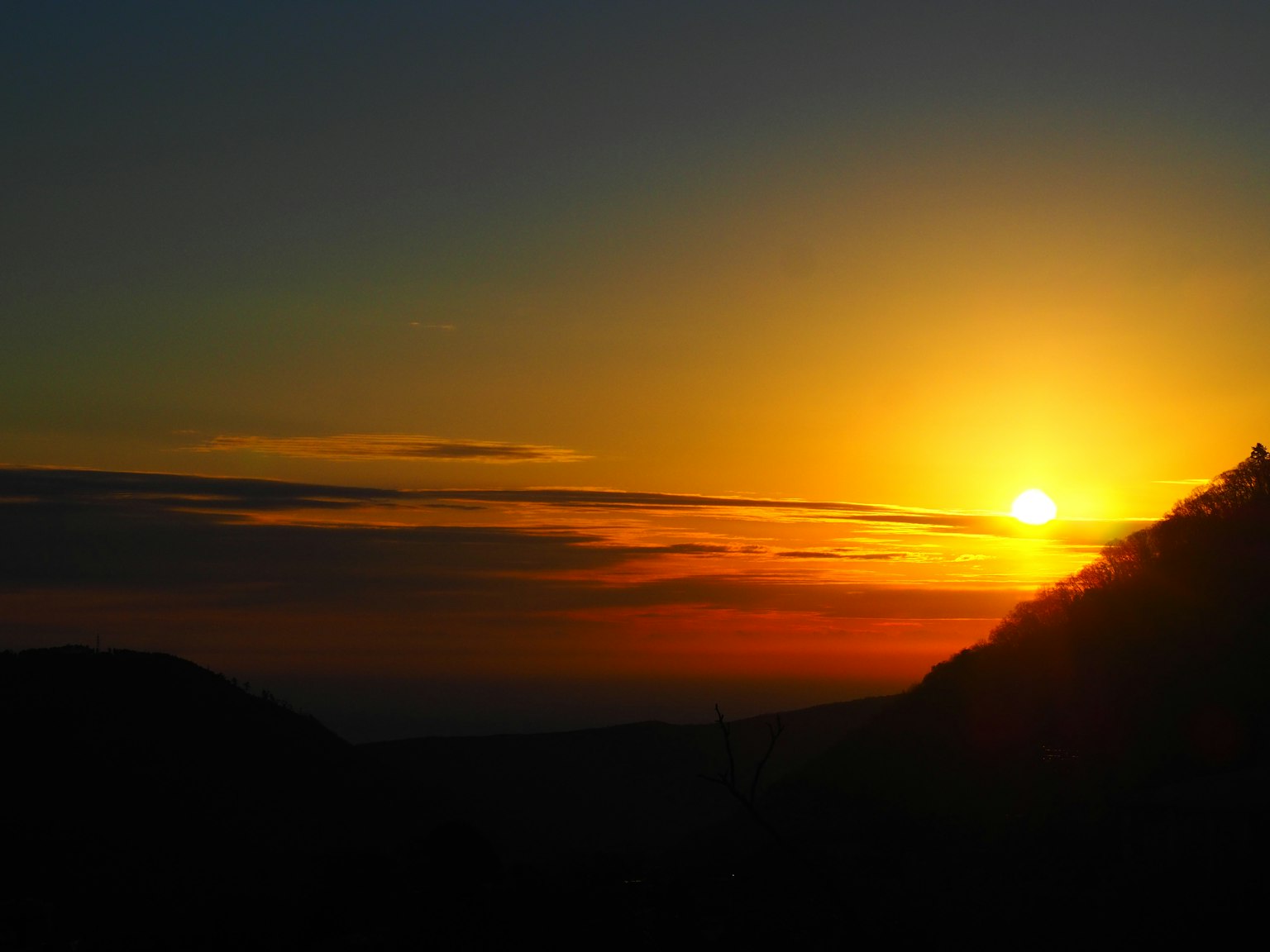 Hermosa vista del atardecer con silueta de montaña y cielo naranja