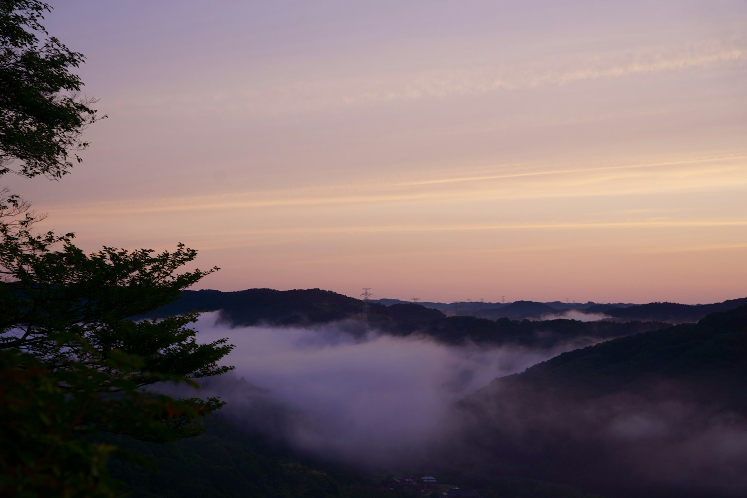 Wunderschöne Landschaft von Bergen, die im Nebel liegen, mit einem lila Himmel