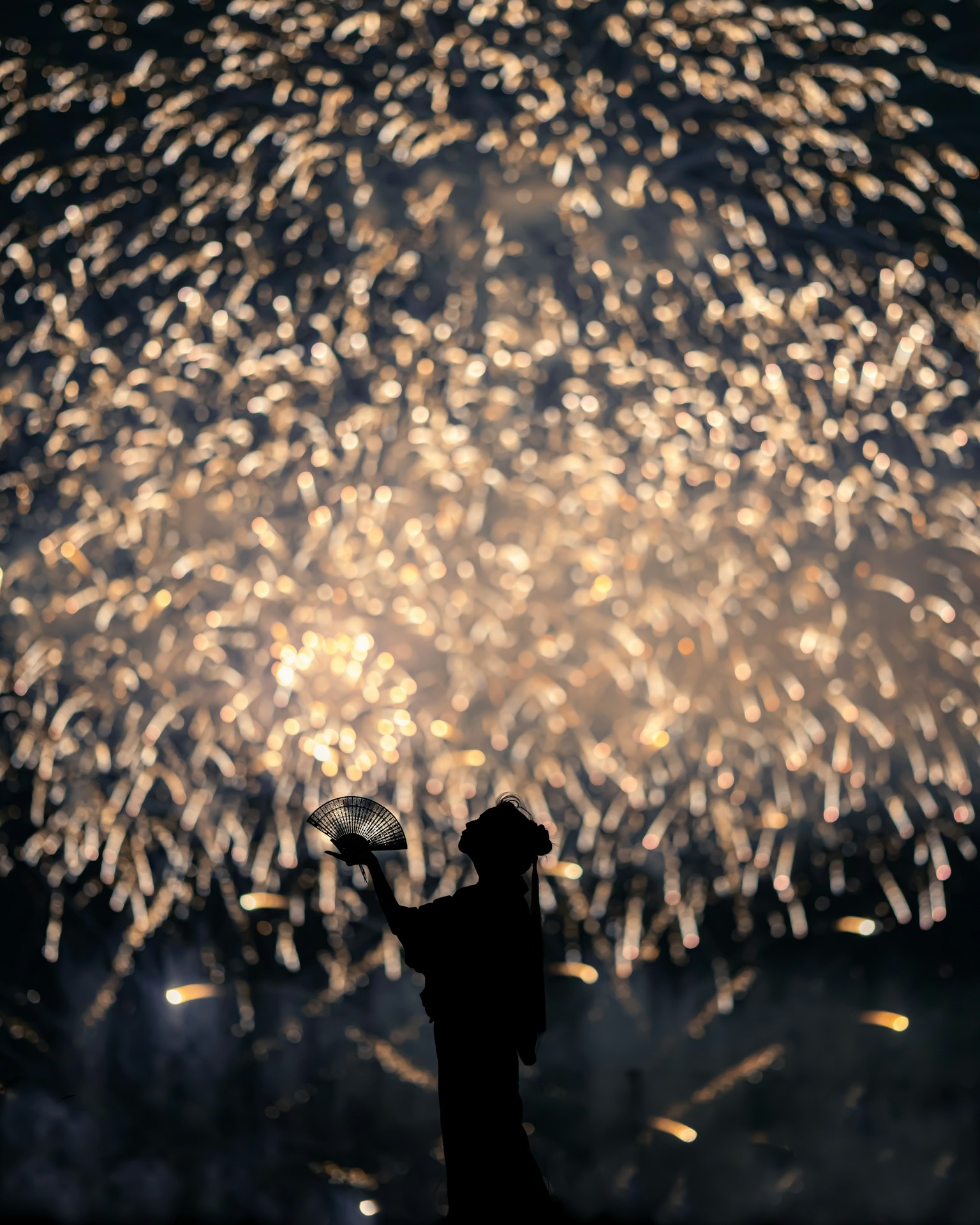Silhouette of a person in front of fireworks with sparkling lights