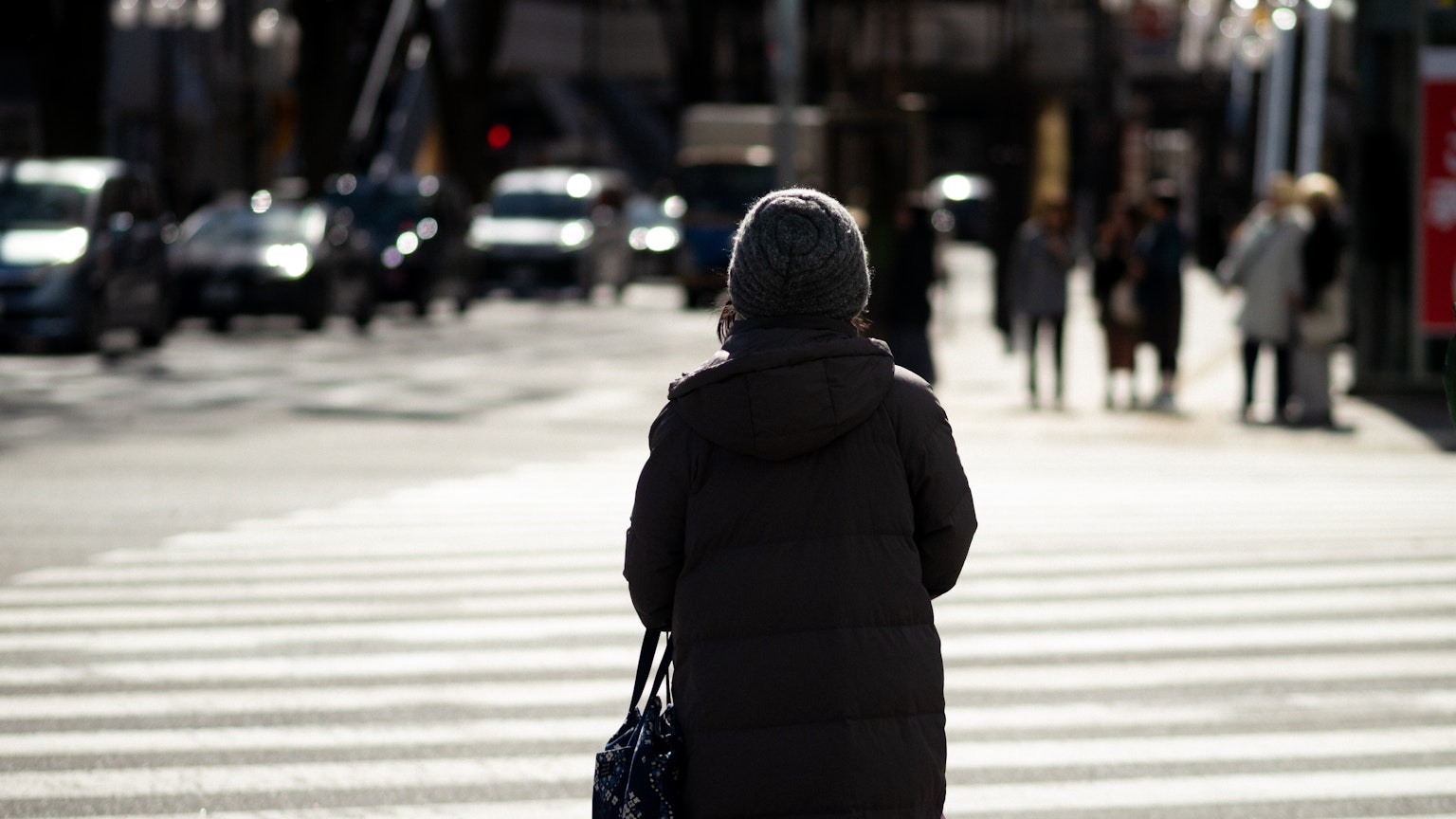 Une femme marchant sur un passage piéton portant un manteau chaud dans un cadre urbain d'hiver