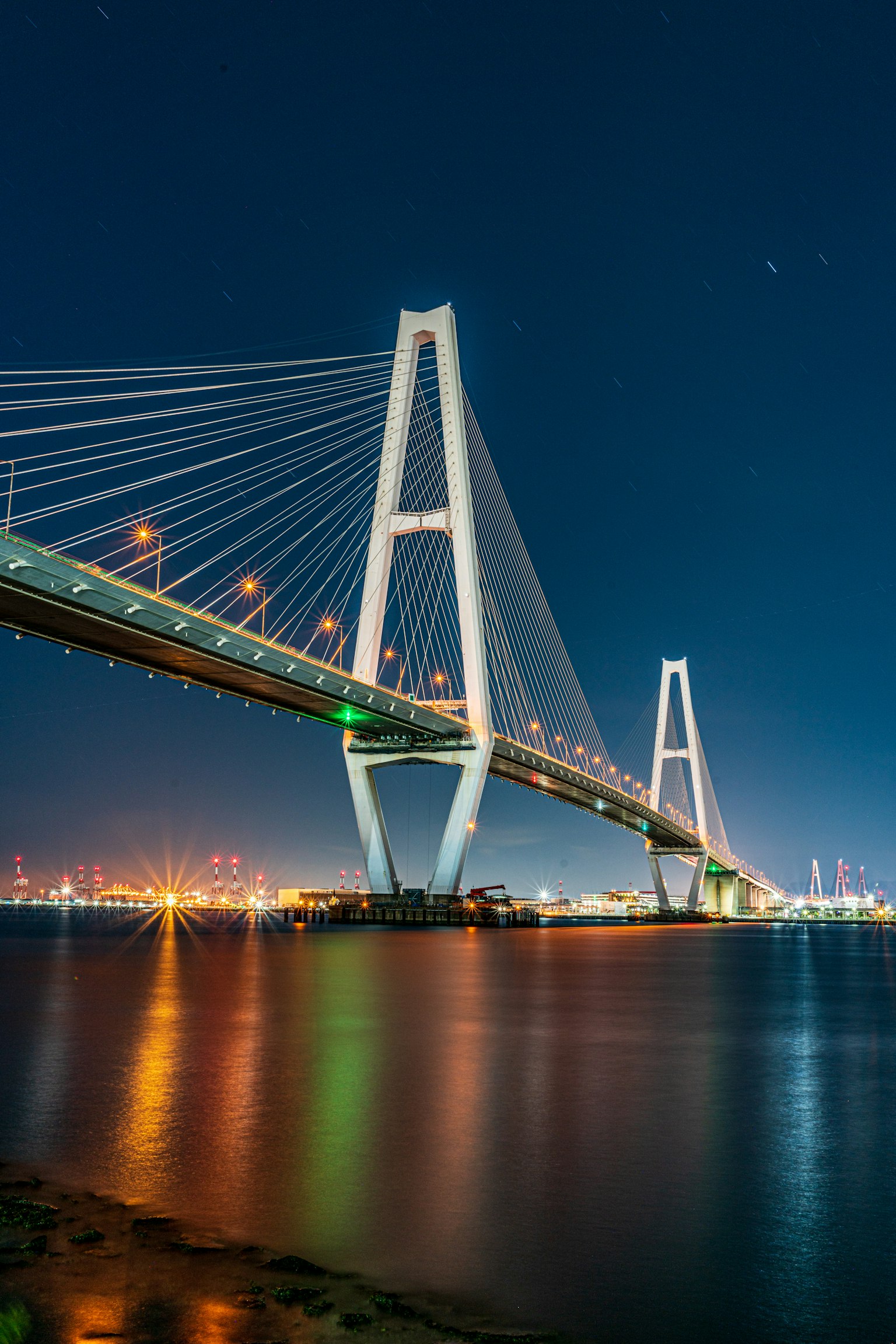 Bellissima vista notturna di un ponte con acqua illuminata e luci della città