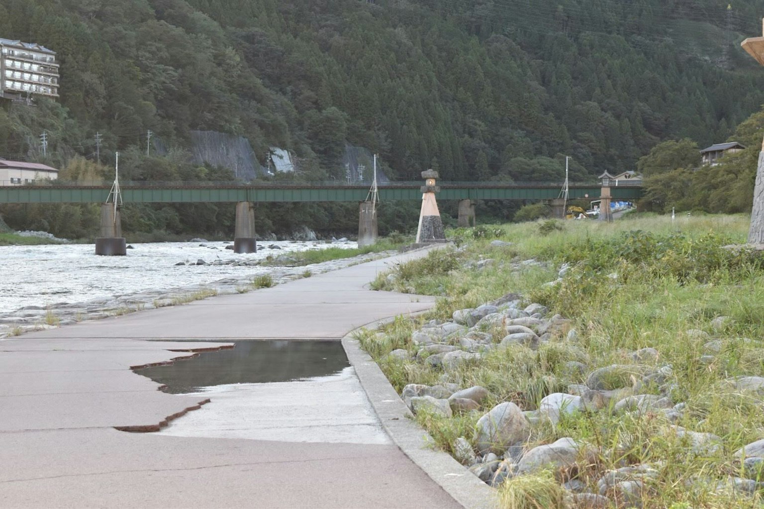 Passeggiata panoramica lungo il fiume con un ponte erba verde e pietre