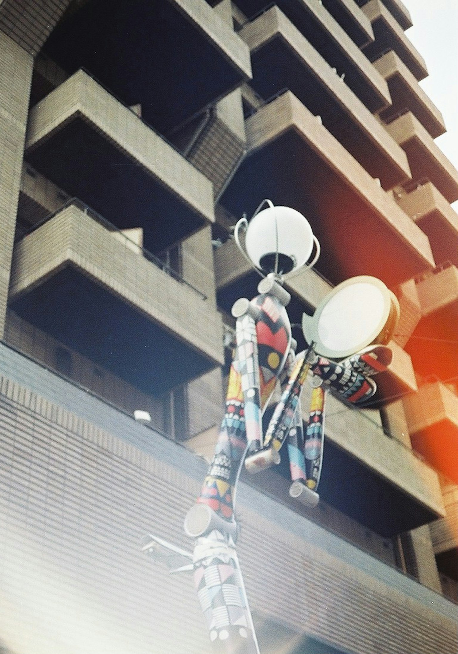 Scultura di robot colorata che tiene tamburi e piatti montata all'esterno di un edificio