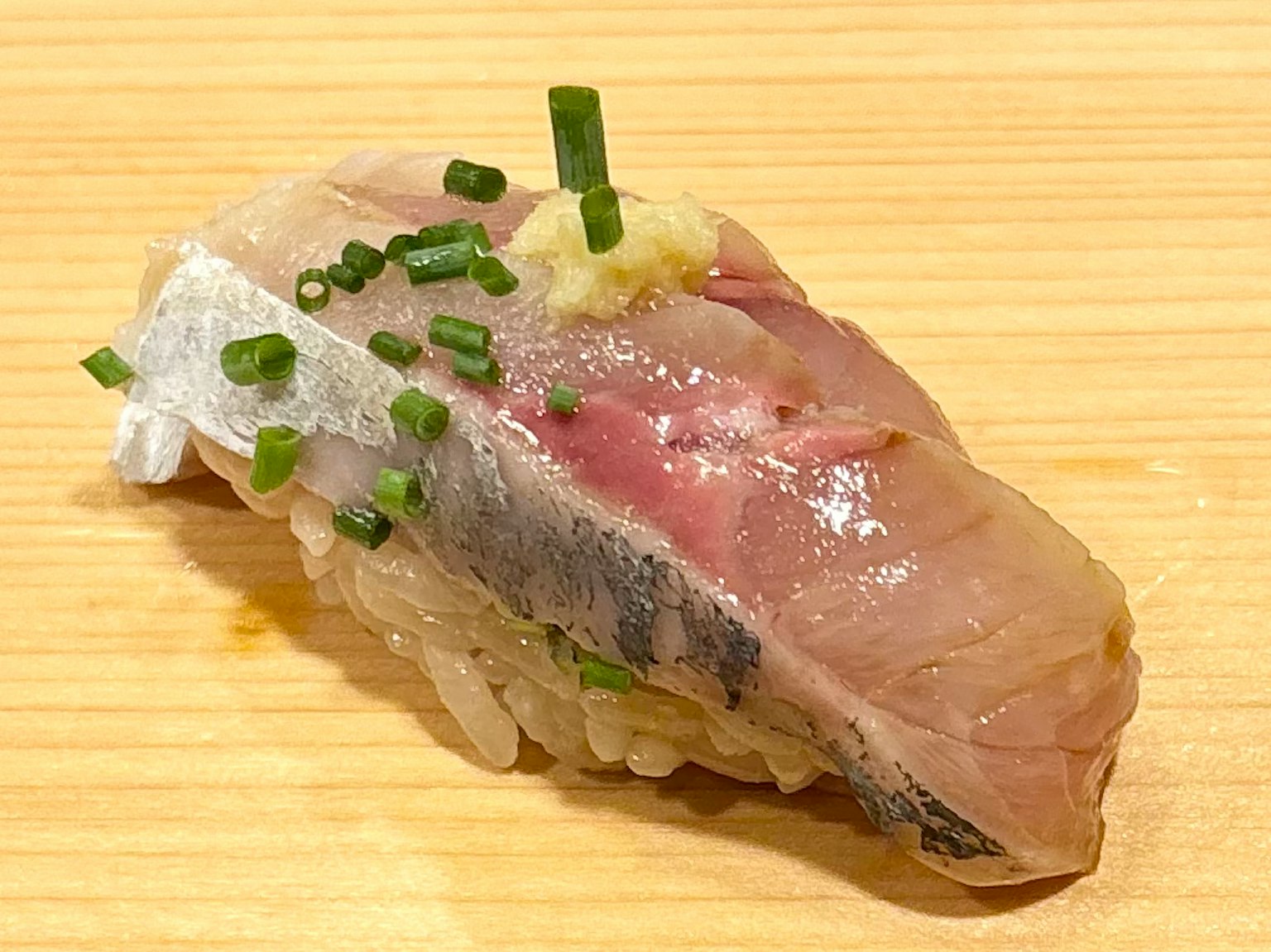 Ein Stück Sushi mit frischem Fisch, garniert mit Frühlingszwiebeln und Ingwer