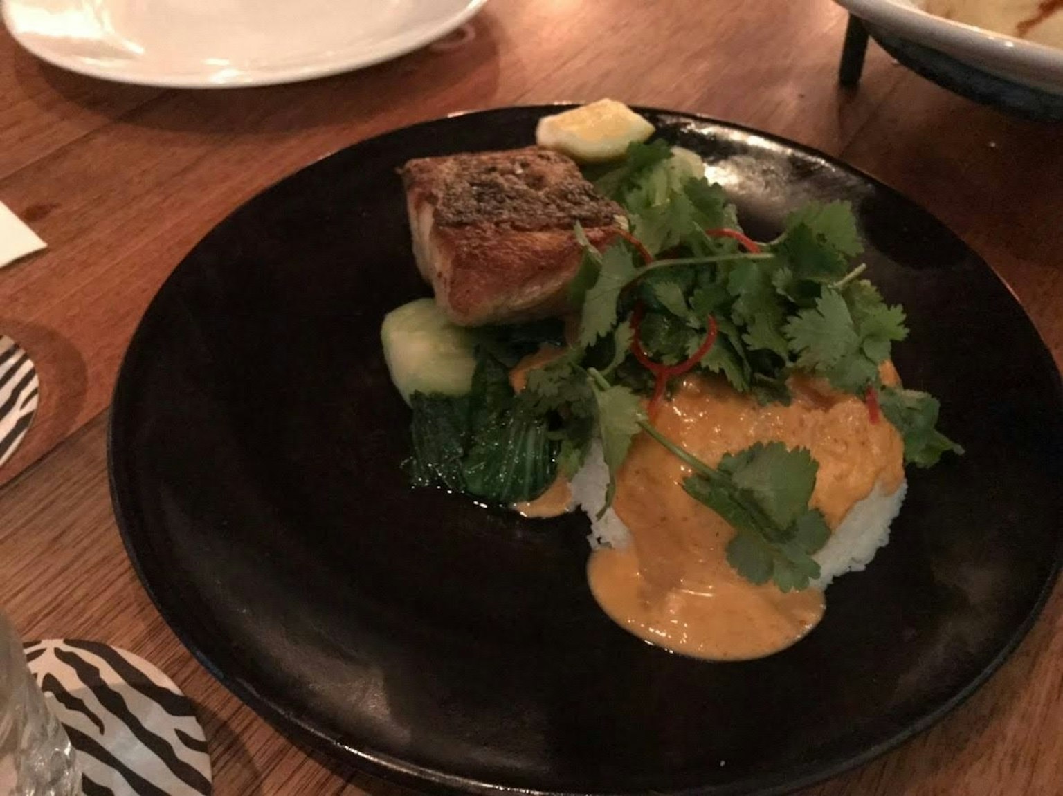 Un piatto ben presentato con pesce, riso e verdure fresche guarnito con coriandolo