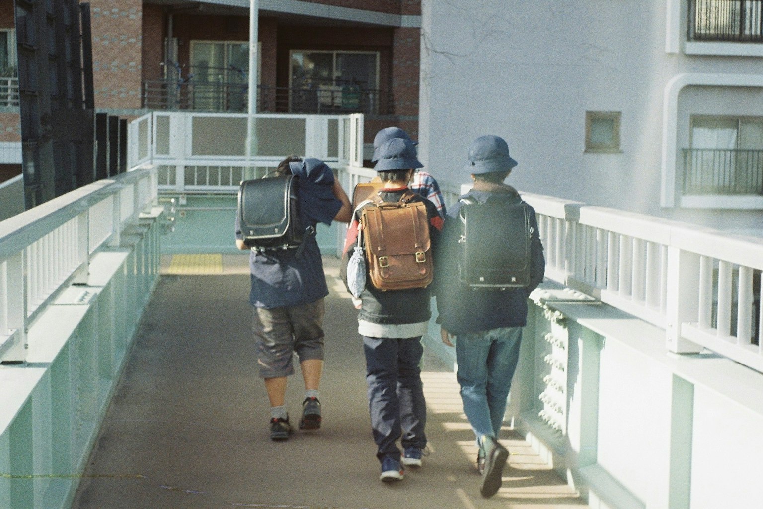 세 명의 젊은이가 배낭을 메고 다리를 걷고 있다