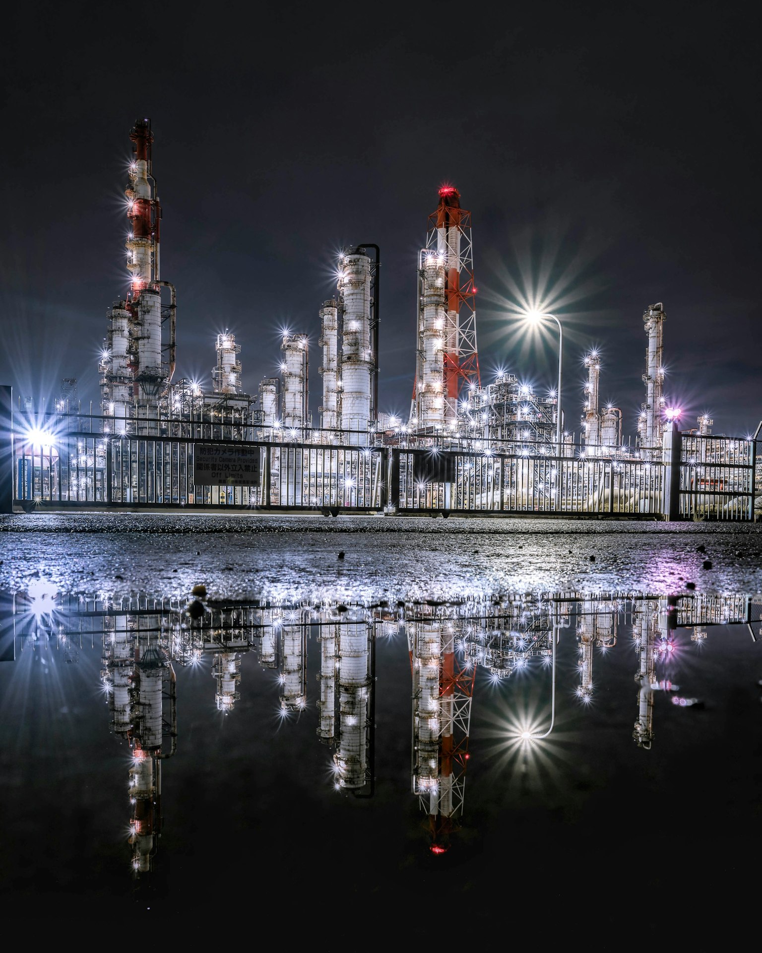 Nighttime industrial plant with illuminated towers reflecting in water