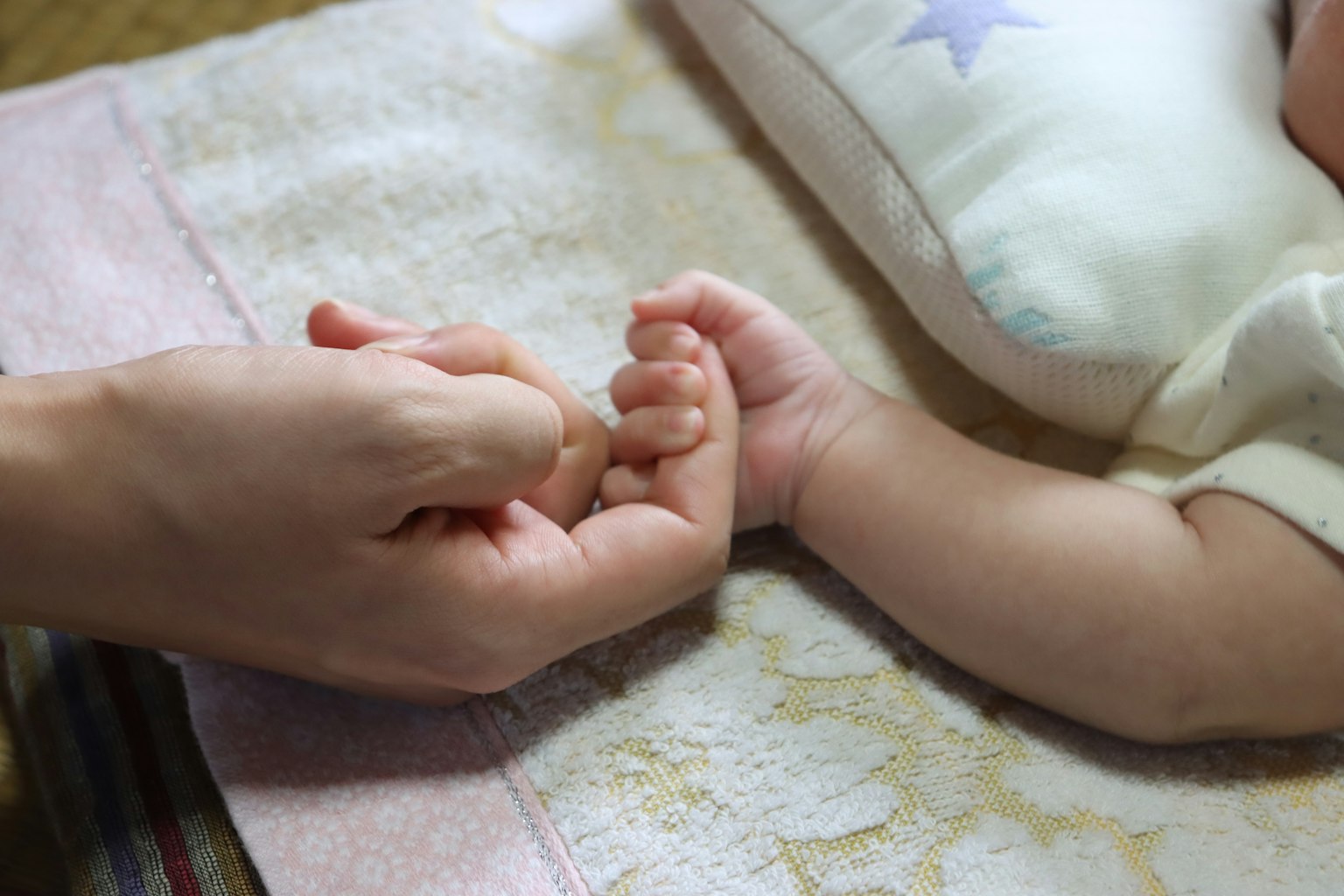 A warm moment of a baby’s tiny hand holding an adult hand