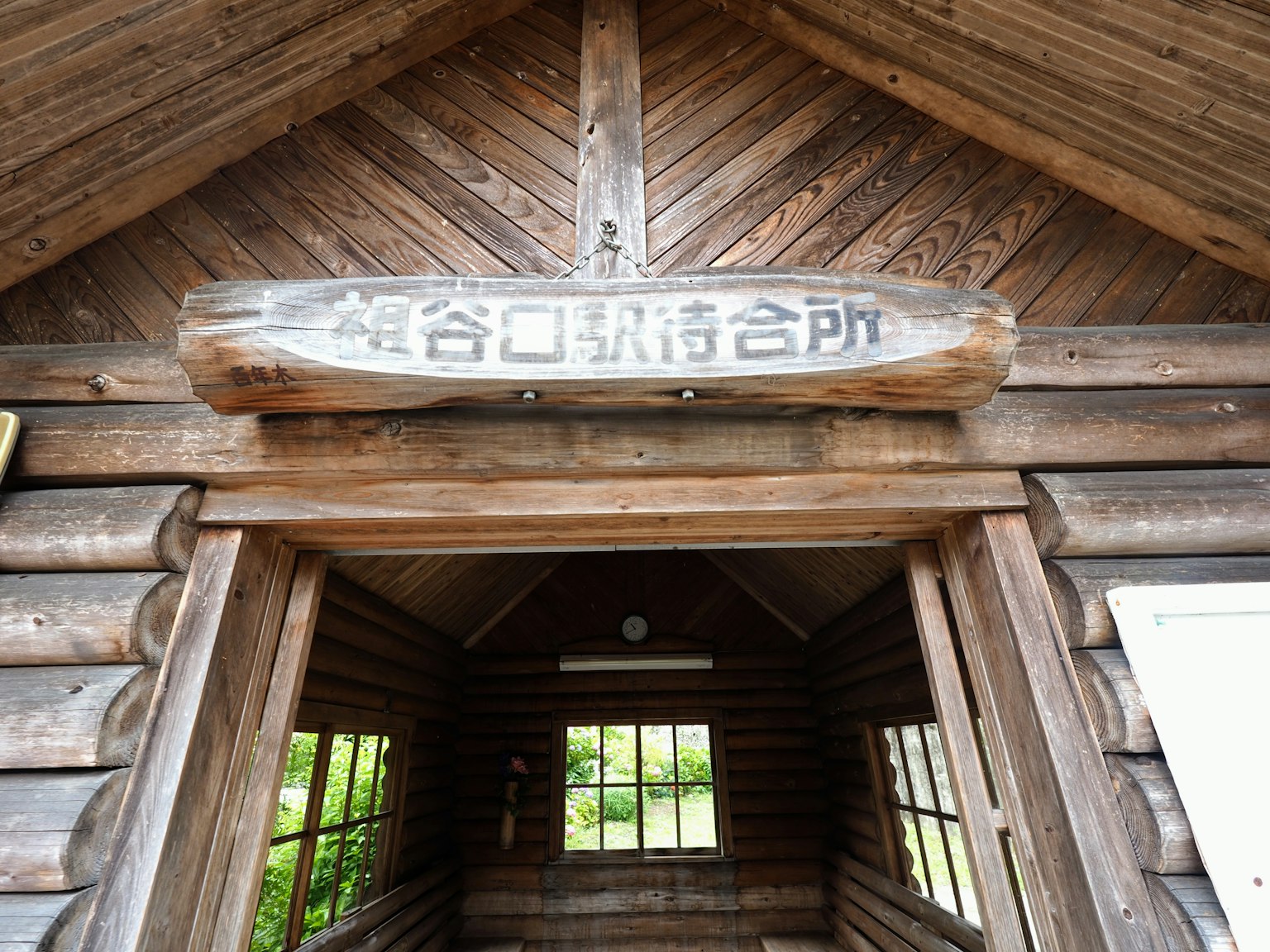 Entrée d'une cabane en bois avec un panneau et plusieurs fenêtres