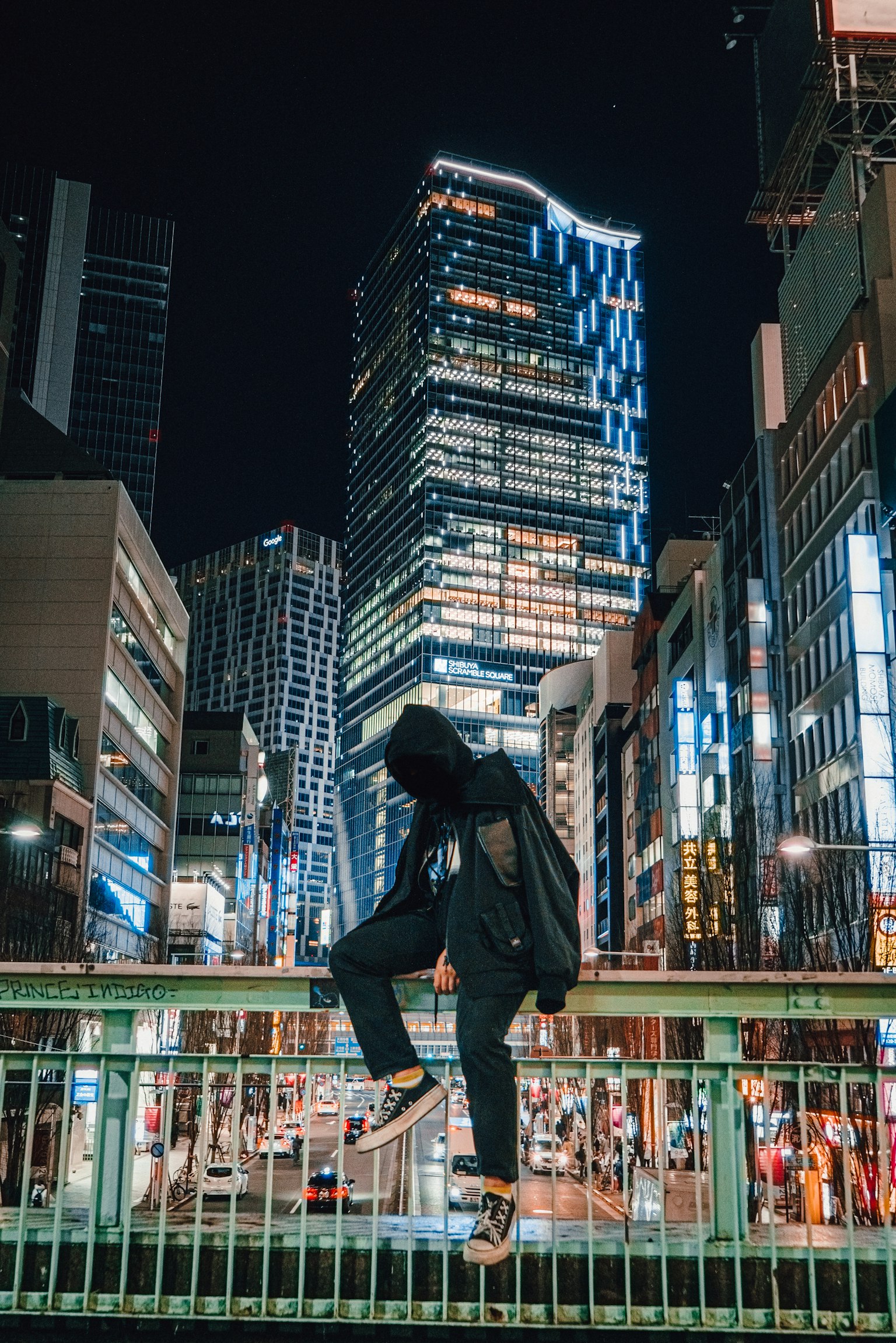 Person standing on a bridge at night with skyscrapers in the background