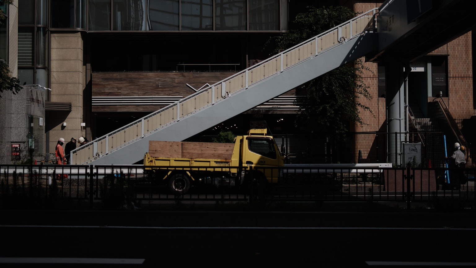 Escena urbana con un camión amarillo y una escalera inclinada