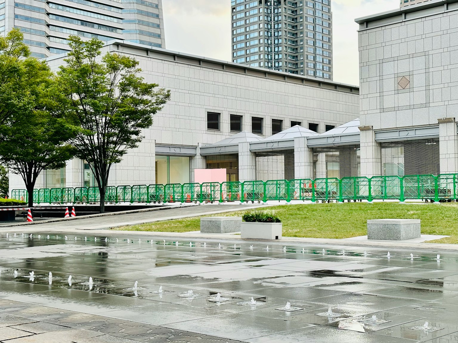 现代建筑前的公共广场有水喷泉和绿色围栏