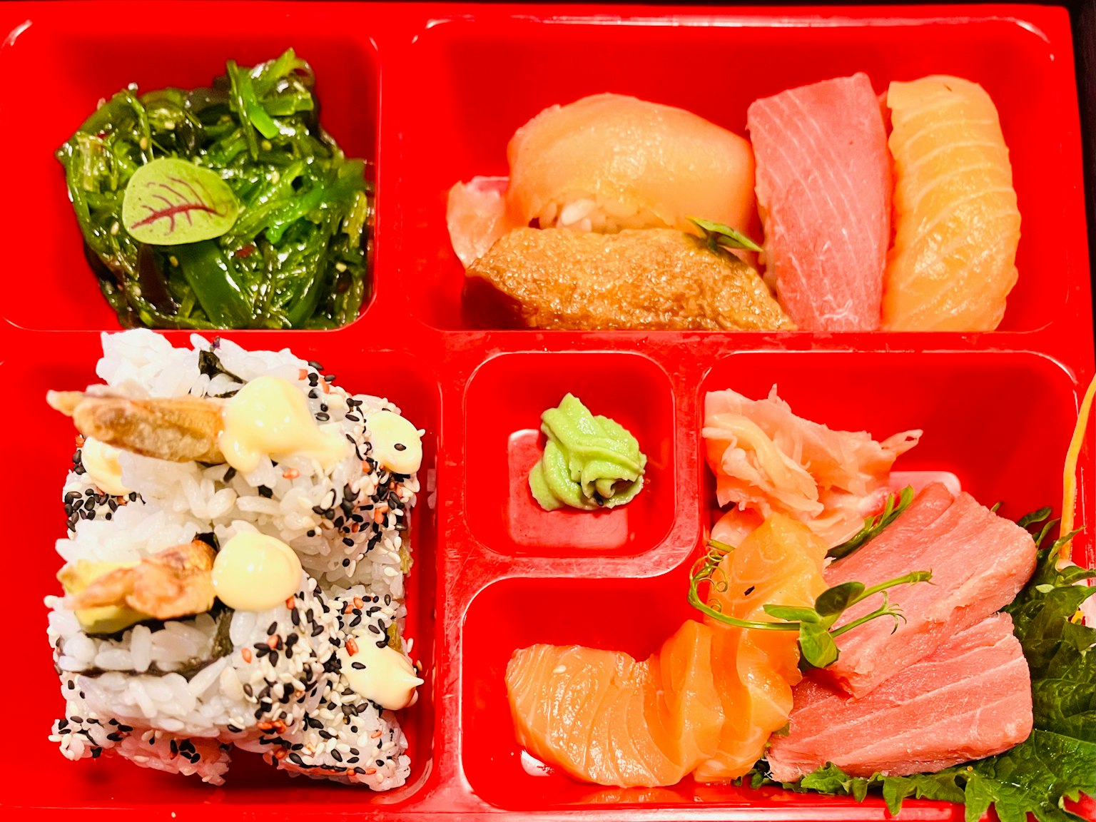 Sushi and sashimi platter arranged in a red bento box