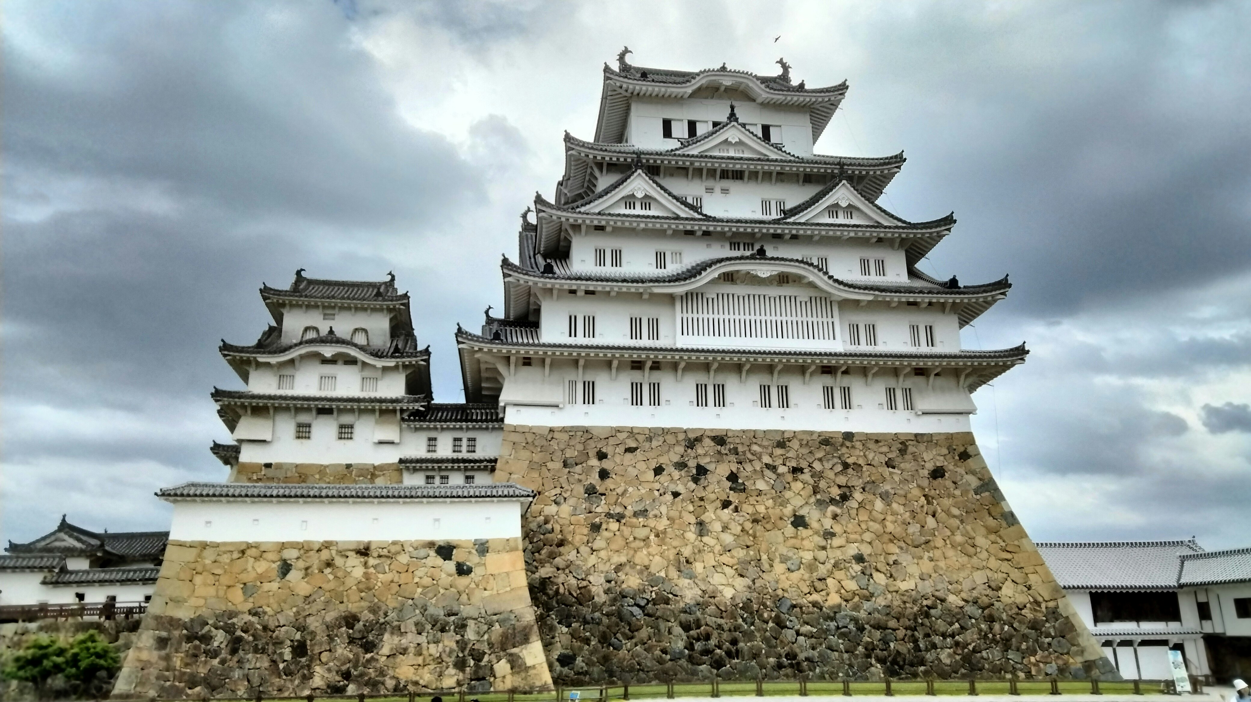 雲の下にそびえる白い城と石垣の天守